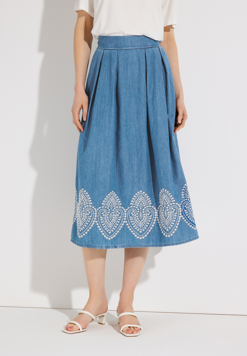Ein MORE & MORE Jeansrock mit weißer Stickerei am Saum wird von einem Model getragen.