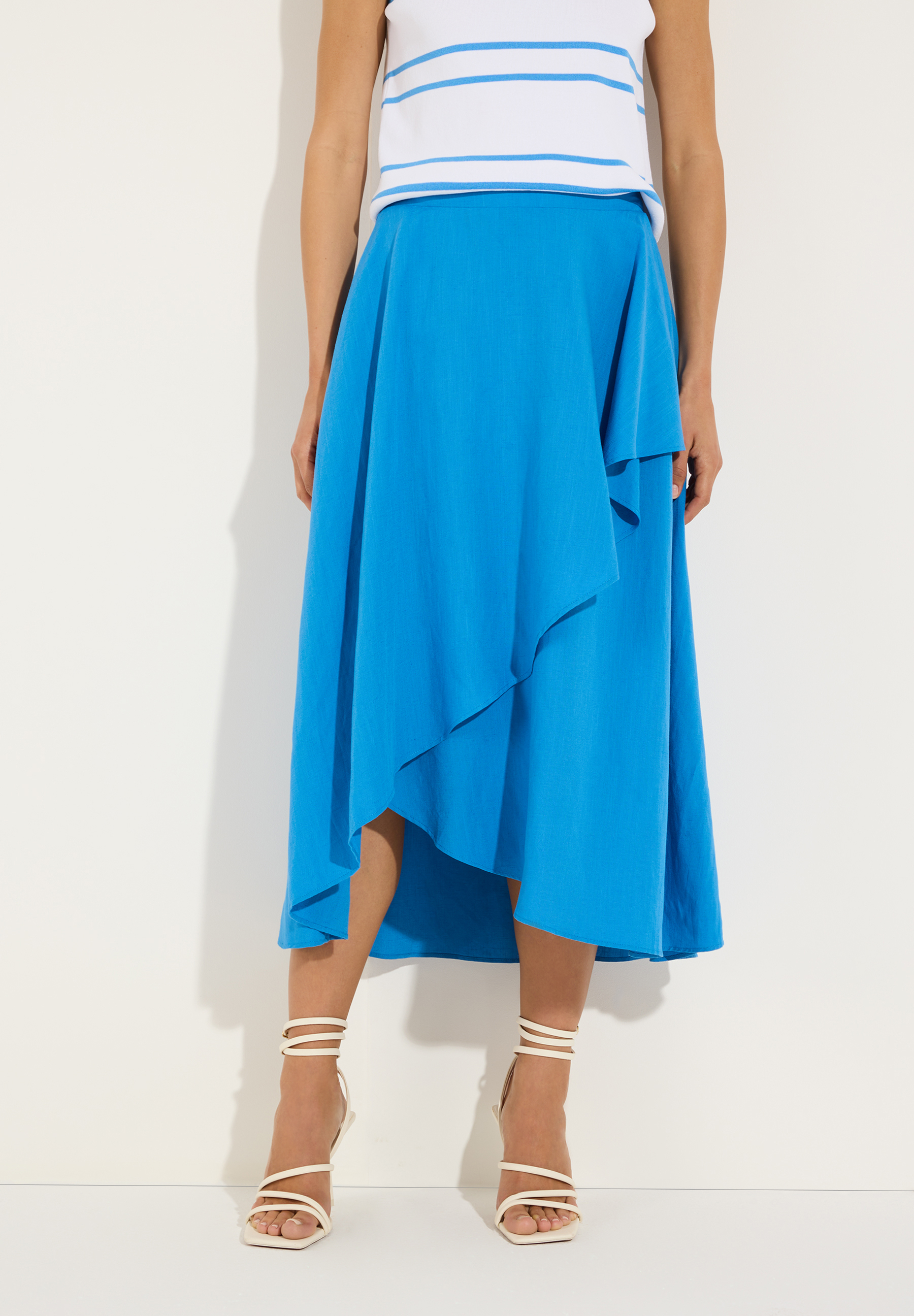 MORE & MORE Midirock in Blau mit asymmetrischem Saum, kombiniert mit gestreiftem Top & cremefarbenen Riemchensandalen. MORE & MORE Midirock in Blau mit asymmetrischem Saum, kombiniert mit gestreiftem Top & cremefarbenen Riemchensandalen.