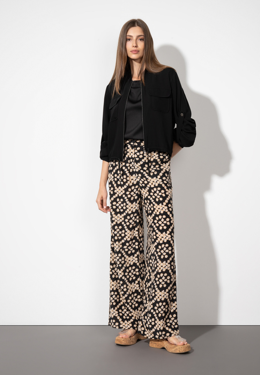 Eine Frau präsentiert MORE & MORE Webware-Hosen mit kühlendem Material und fließendem Fall vor einem hellen Hintergrund. Eine Frau präsentiert MORE & MORE Webware-Hosen mit kühlendem Material und fließendem Fall vor einem hellen Hintergrund.