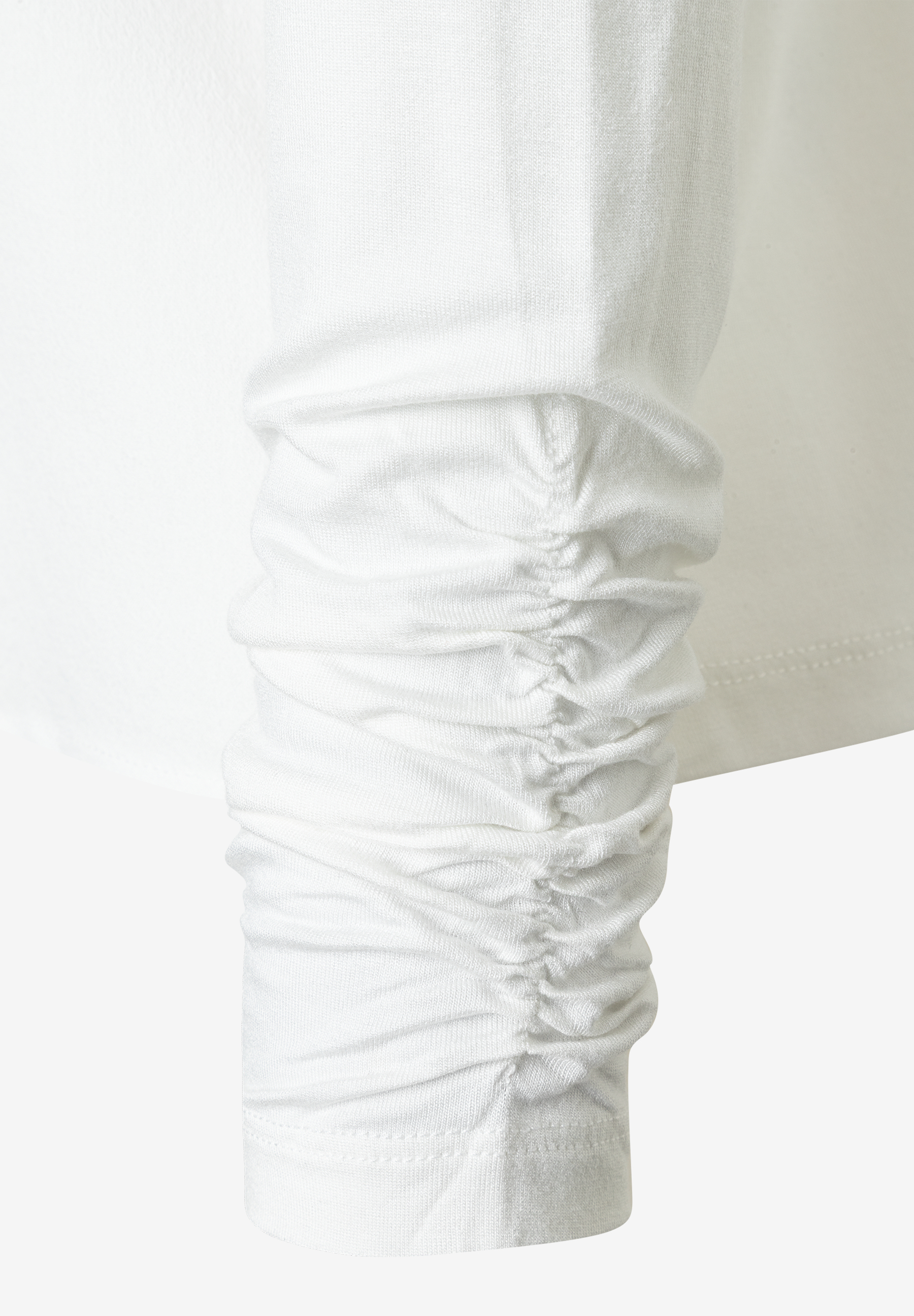 Detailaufnahme des gerafften Ärmels einer weißen MORE & MORE Bluse. Detailaufnahme des gerafften Ärmels einer weißen MORE & MORE Bluse.