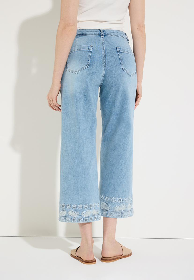 Eine Frau von hinten in MORE & MORE Jeanshose aus Denim mit Verzierungen am Saum. Eine Frau von hinten in MORE & MORE Jeanshose aus Denim mit Verzierungen am Saum.