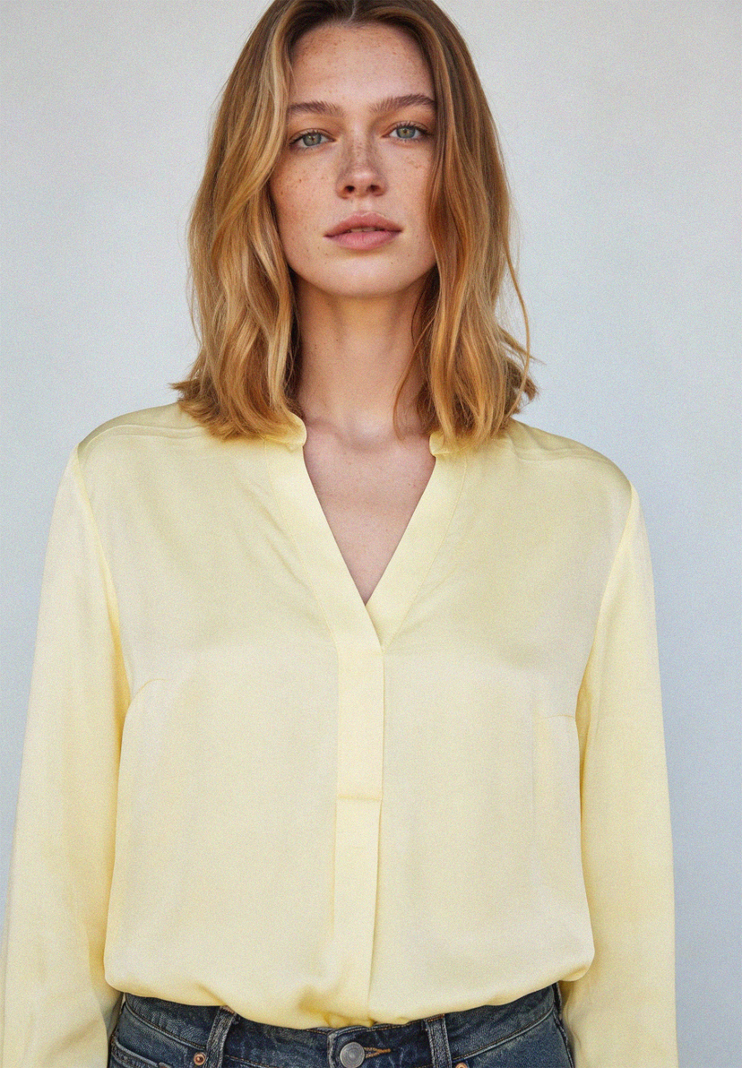 Eine Frau trägt eine hellgelbe Satinbluse von MORE & MORE. Das Material ist fließend und glänzend. Eine Frau trägt eine hellgelbe Satinbluse von MORE & MORE. Das Material ist fließend und glänzend.