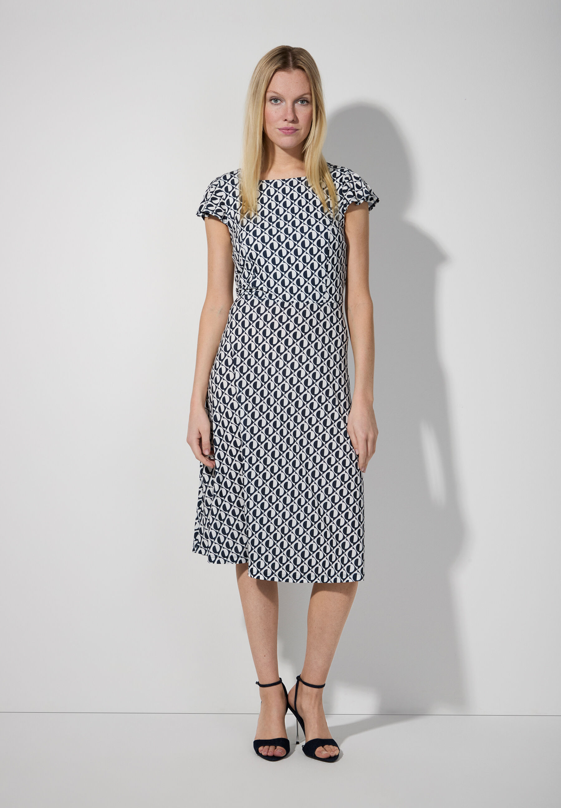 Eine Frau in einem gemusterten Jersey-Kleid von MORE & MORE, mit Stretch für Komfort. Eine Frau in einem gemusterten Jersey-Kleid von MORE & MORE, mit Stretch für Komfort.