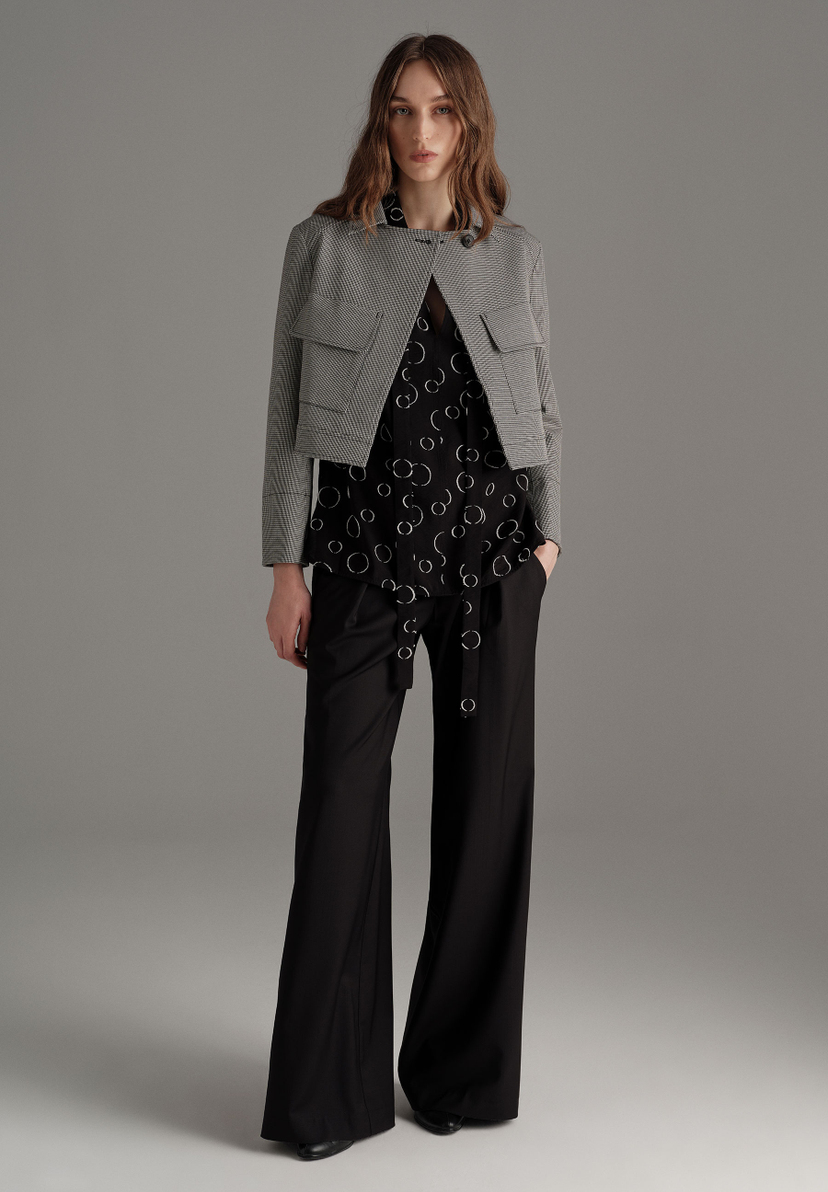 Eine Frau trägt einen MORE & MORE Blazer über einem Oberteil mit Kreismuster und eine schwarze Hose. Eine Frau trägt einen MORE & MORE Blazer über einem Oberteil mit Kreismuster und eine schwarze Hose.