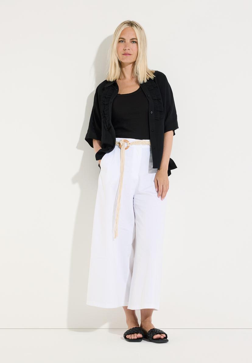 MORE & MORE Bluse: Eine blonde Frau trägt eine schwarze Kurzarm-Bluse über einem Tanktop, weiße Hosen und schwarze Sandalen. MORE & MORE Bluse: Eine blonde Frau trägt eine schwarze Kurzarm-Bluse über einem Tanktop, weiße Hosen und schwarze Sandalen.