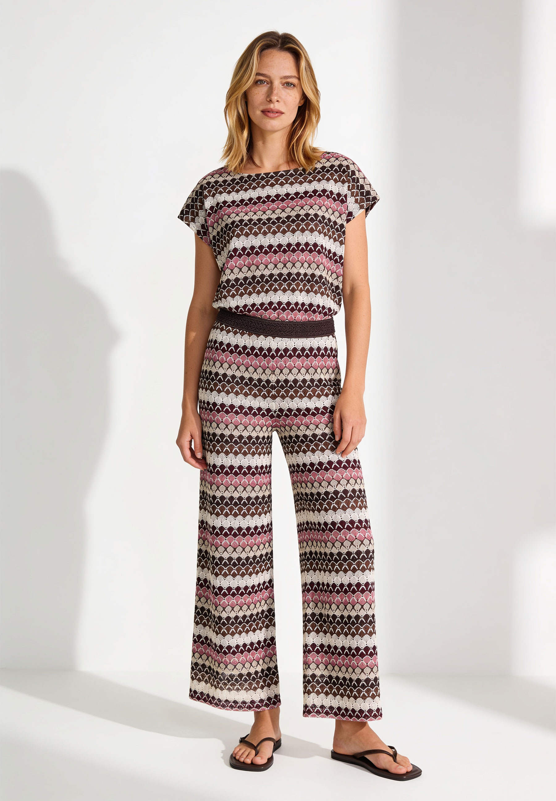 AI generated - MORE & MORE gemusterter Strick-Jumpsuit in Dunkelbraun, Rosa und Beige. Das Oberteil hat kurze Ärmel, weite Beine. AI generated - MORE & MORE gemusterter Strick-Jumpsuit in Dunkelbraun, Rosa und Beige. Das Oberteil hat kurze Ärmel, weite Beine.