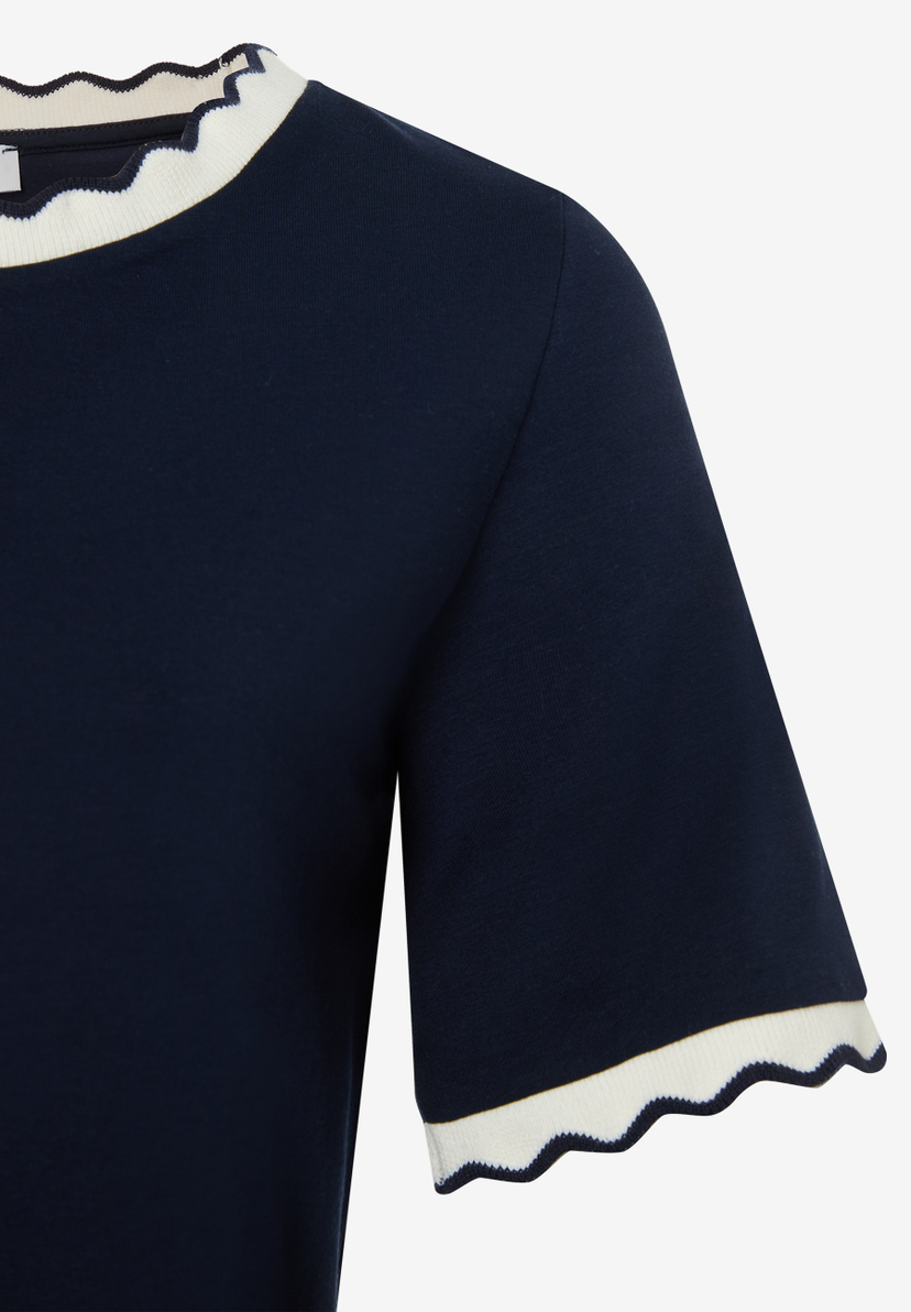 Nahaufnahme eines dunkelblauen MORE & MORE Oberteils mit gewelltem, weißem Kragen und Ärmelbündchen. Nahaufnahme eines dunkelblauen MORE & MORE Oberteils mit gewelltem, weißem Kragen und Ärmelbündchen.