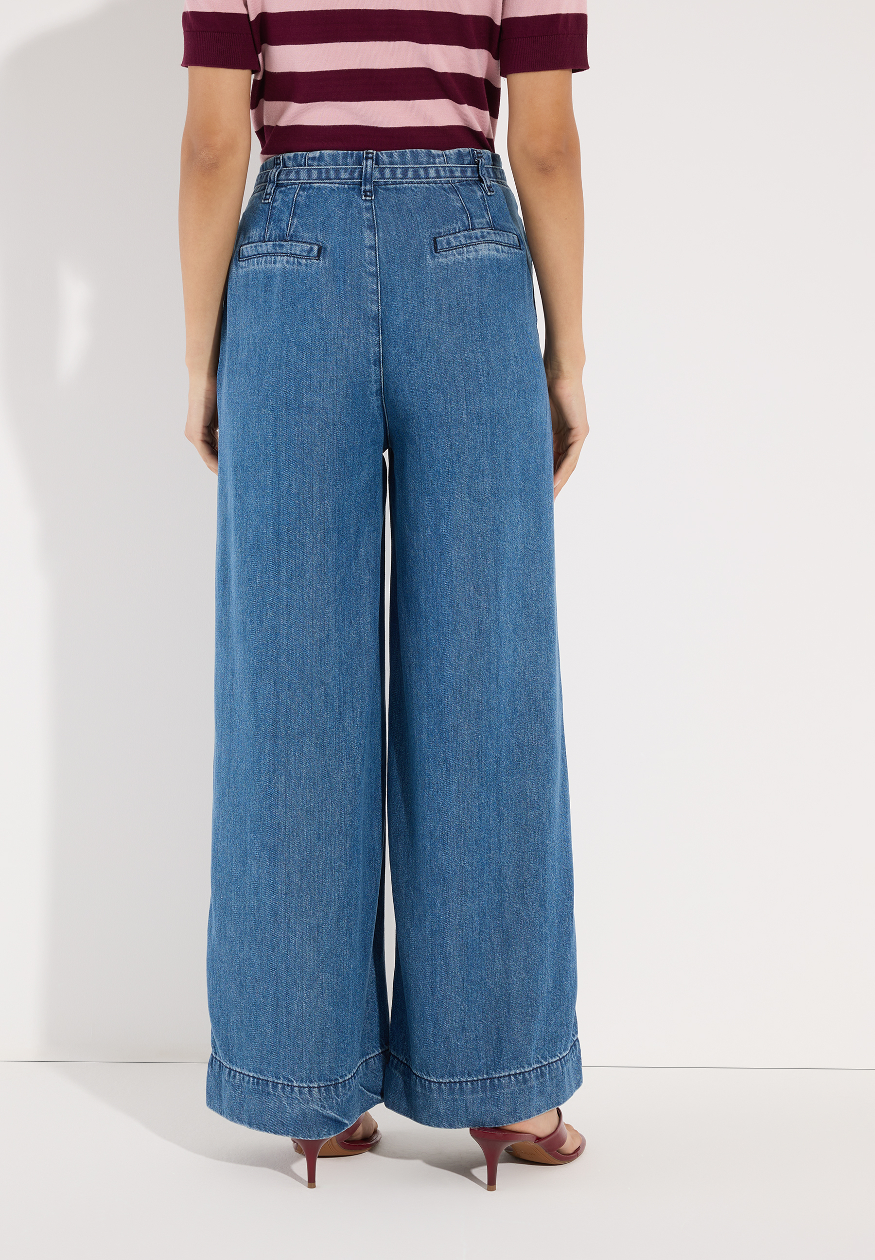 MORE & MORE Jeans aus Denim. Detailansicht des Oberteils einer jungen Frau von der Seite, das eine Jeanshose und ein weißes Hemd trägt. MORE & MORE Jeans aus Denim. Detailansicht des Oberteils einer jungen Frau von der Seite, das eine Jeanshose und ein weißes Hemd trägt.