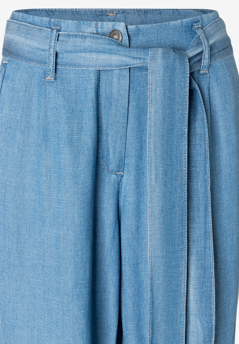 Nahaufnahme einer hellblauen MORE & MORE Hose mit Denim-Bindegürtel. Nahaufnahme einer hellblauen MORE & MORE Hose mit Denim-Bindegürtel.