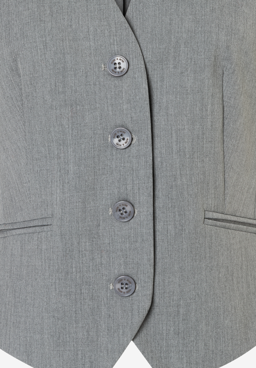 Nahaufnahme eines grauen Blazers von MORE & MORE mit Knöpfen und Taschen-Details. Nahaufnahme eines grauen Blazers von MORE & MORE mit Knöpfen und Taschen-Details.
