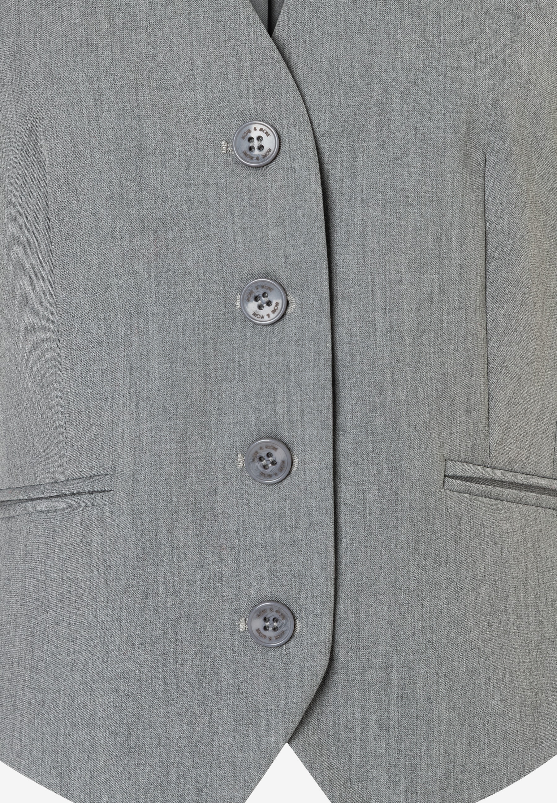 Nahaufnahme eines grauen Blazers von MORE & MORE mit Knöpfen und Taschen-Details. Nahaufnahme eines grauen Blazers von MORE & MORE mit Knöpfen und Taschen-Details.