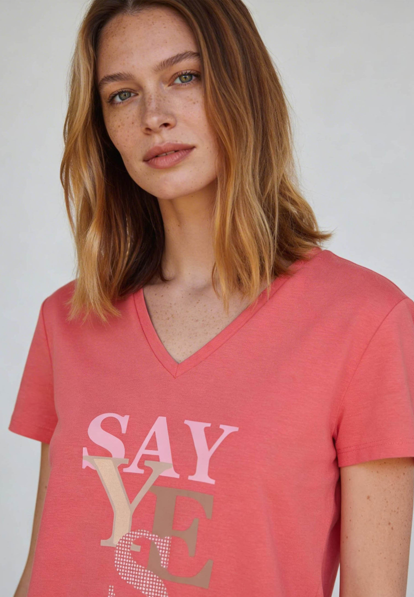 AI generated - Nahaufnahme einer Frau, die ein Jersey-Top von MORE & MORE mit V-Ausschnitt und dem Aufdruck 'Say Yes' trägt. AI generated - Nahaufnahme einer Frau, die ein Jersey-Top von MORE & MORE mit V-Ausschnitt und dem Aufdruck 'Say Yes' trägt.