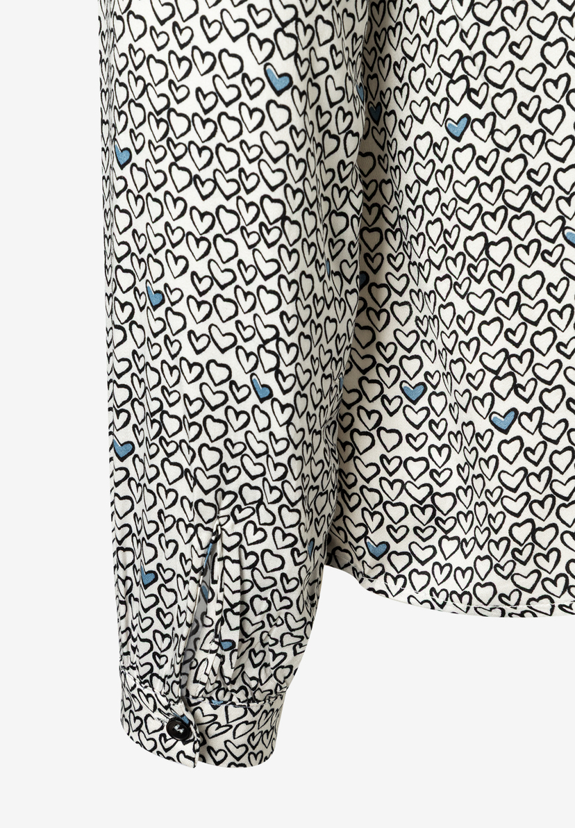 Nahaufnahme einer MORE & MORE Bluse mit Herzmuster und Manschettenknopf. Nahaufnahme einer MORE & MORE Bluse mit Herzmuster und Manschettenknopf.