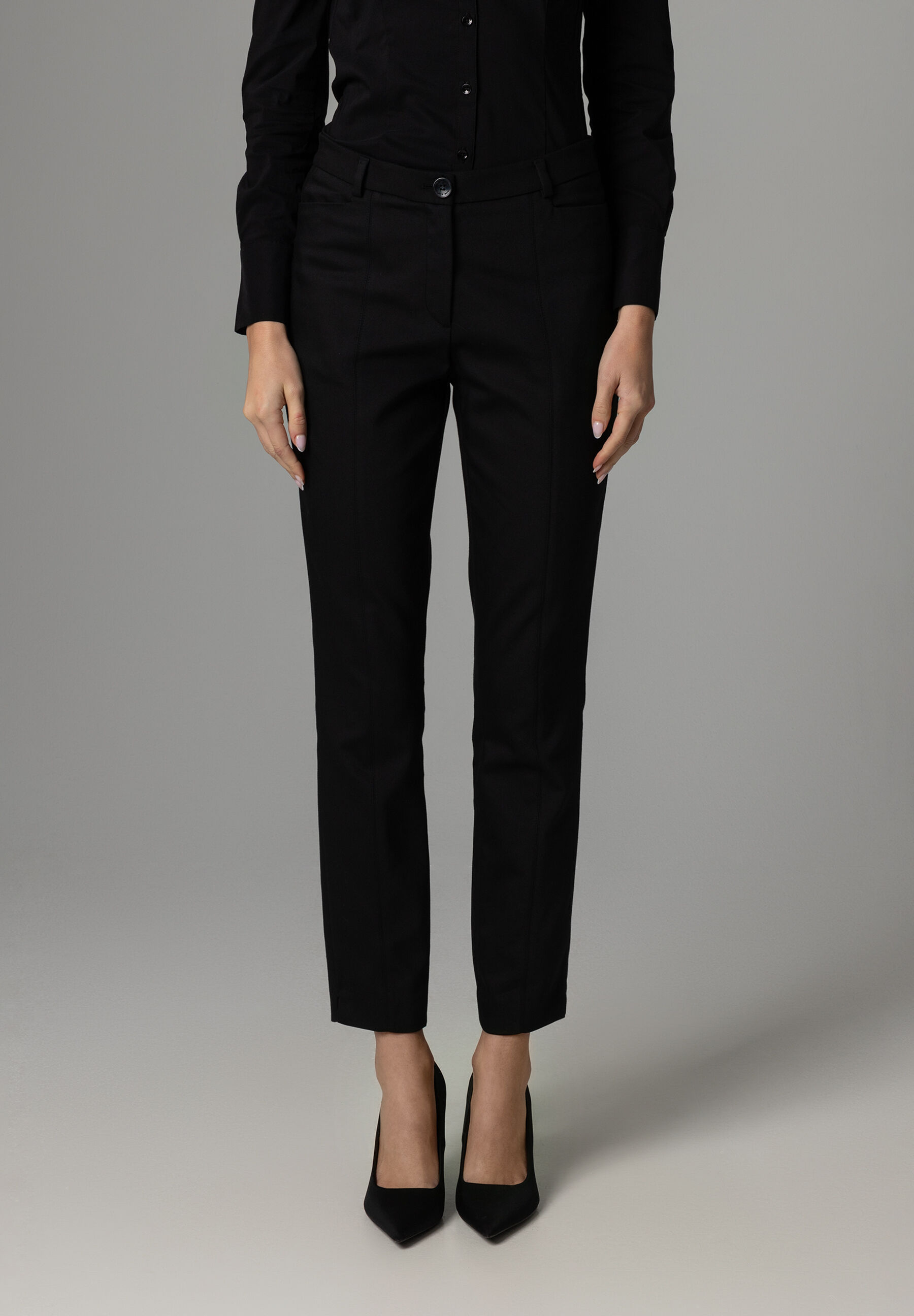 Eine Person trägt eine schwarze MORE & MORE Hose aus Baumwollmischung und schwarze Schuhe vor einem grauen Hintergrund. Eine Person trägt eine schwarze MORE & MORE Hose aus Baumwollmischung und schwarze Schuhe vor einem grauen Hintergrund.