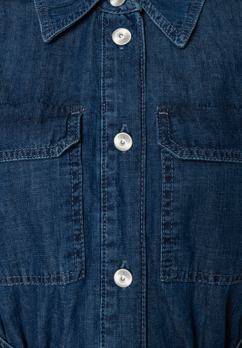 Detailaufnahme eines Jeansoberteils von MORE & MORE mit Brusttaschen und silberfarbenen Knöpfen. Detailaufnahme eines Jeansoberteils von MORE & MORE mit Brusttaschen und silberfarbenen Knöpfen.