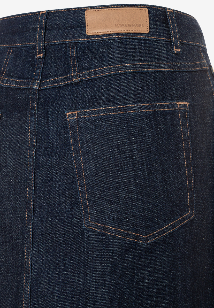Nahaufnahme der Rückseite eines MORE & MORE Jeansrocks mit Tasche und Logo-Etikett am Bund. Nahaufnahme der Rückseite eines MORE & MORE Jeansrocks mit Tasche und Logo-Etikett am Bund.