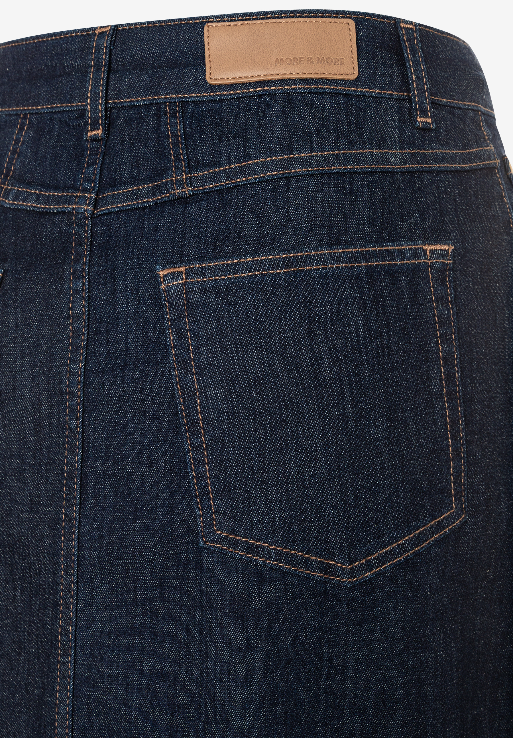 Nahaufnahme der Rückseite eines MORE & MORE Jeansrocks mit Tasche und Logo-Etikett am Bund. Nahaufnahme der Rückseite eines MORE & MORE Jeansrocks mit Tasche und Logo-Etikett am Bund.