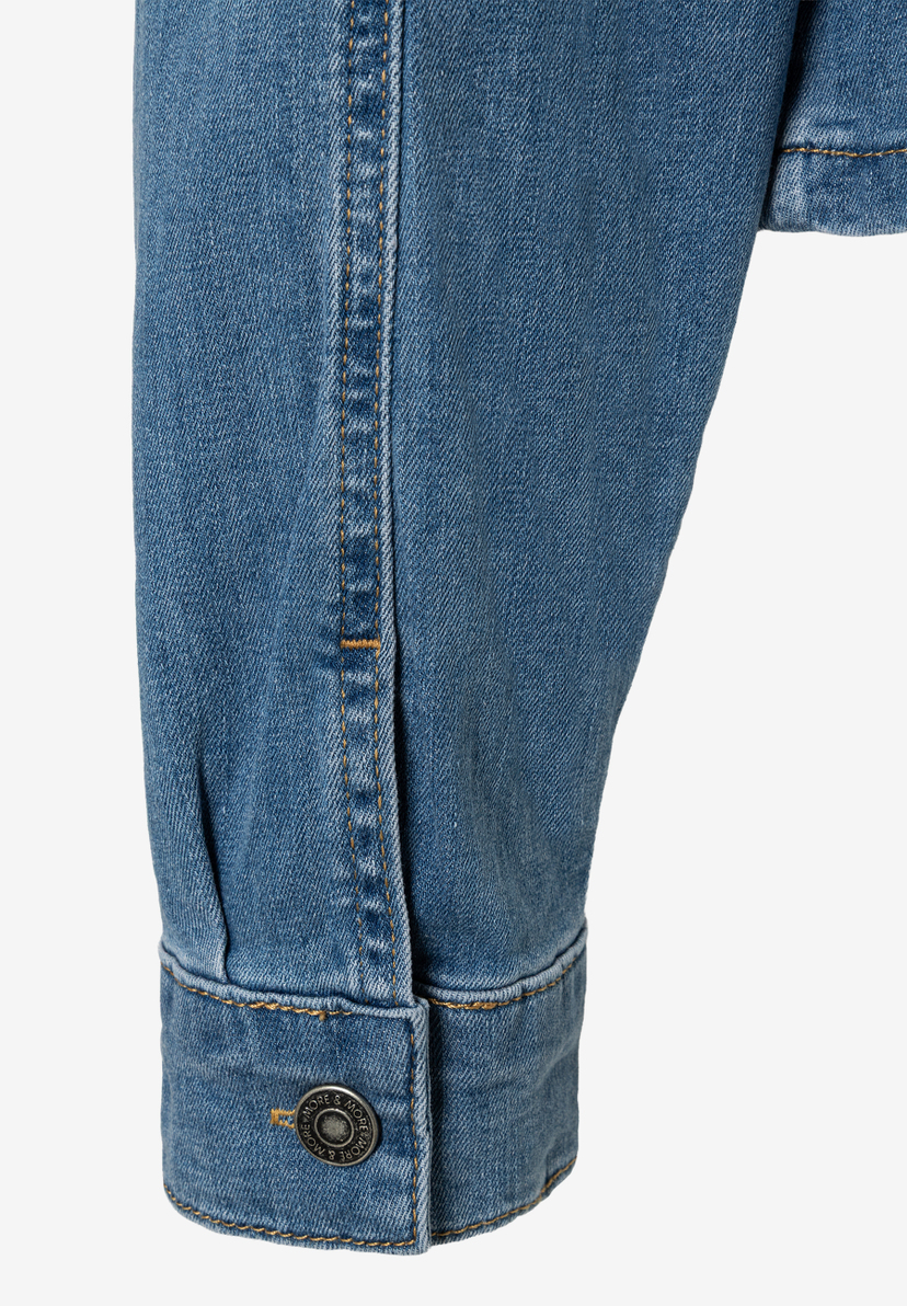 Detailansicht einer MORE & MORE Jeansjacke, Fokus auf Ärmel und Knopf. Detailansicht einer MORE & MORE Jeansjacke, Fokus auf Ärmel und Knopf.