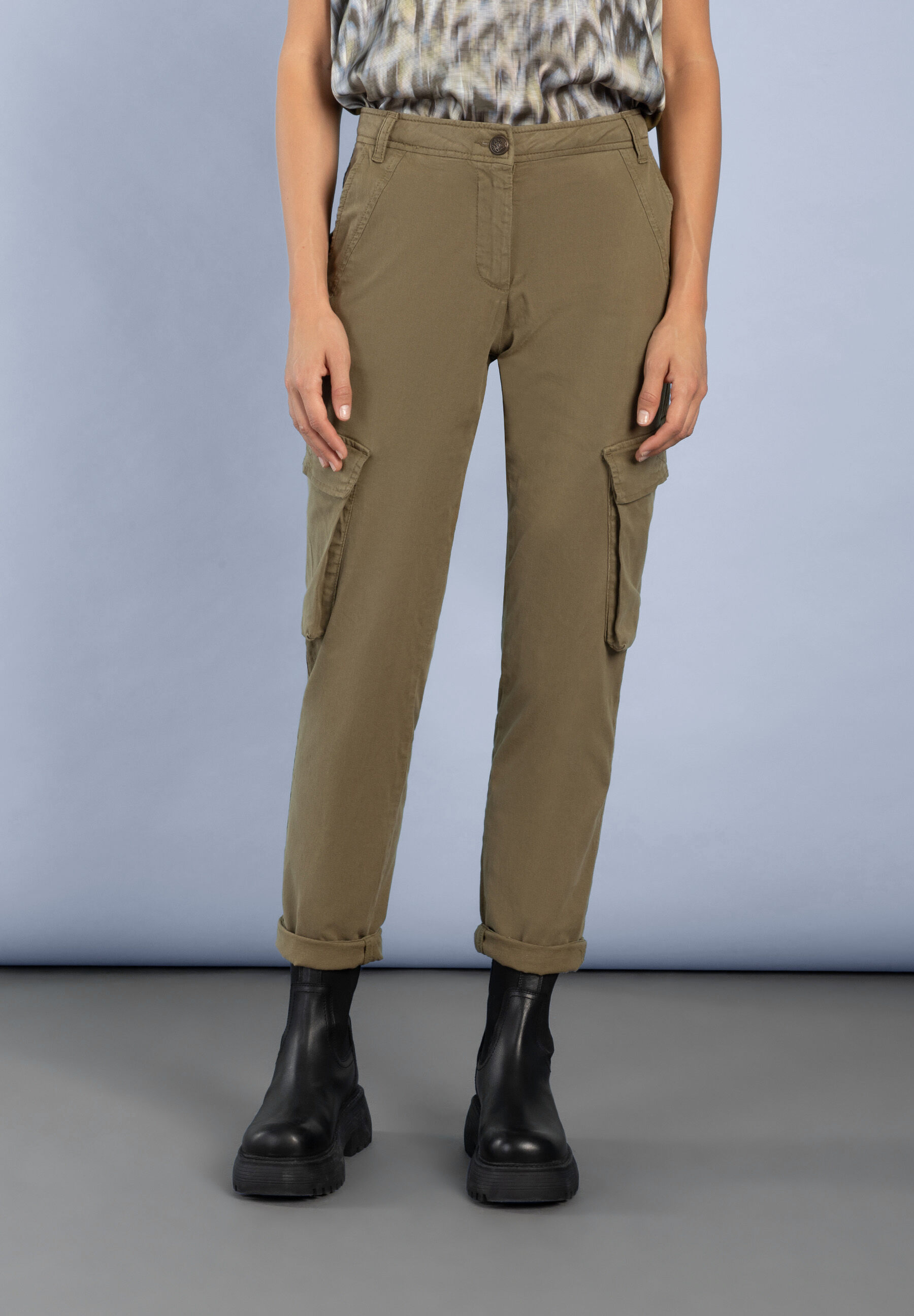 Eine Frau trägt MORE & MORE Cargo-Jeans aus Stretch-Denim und schwarze Stiefel.