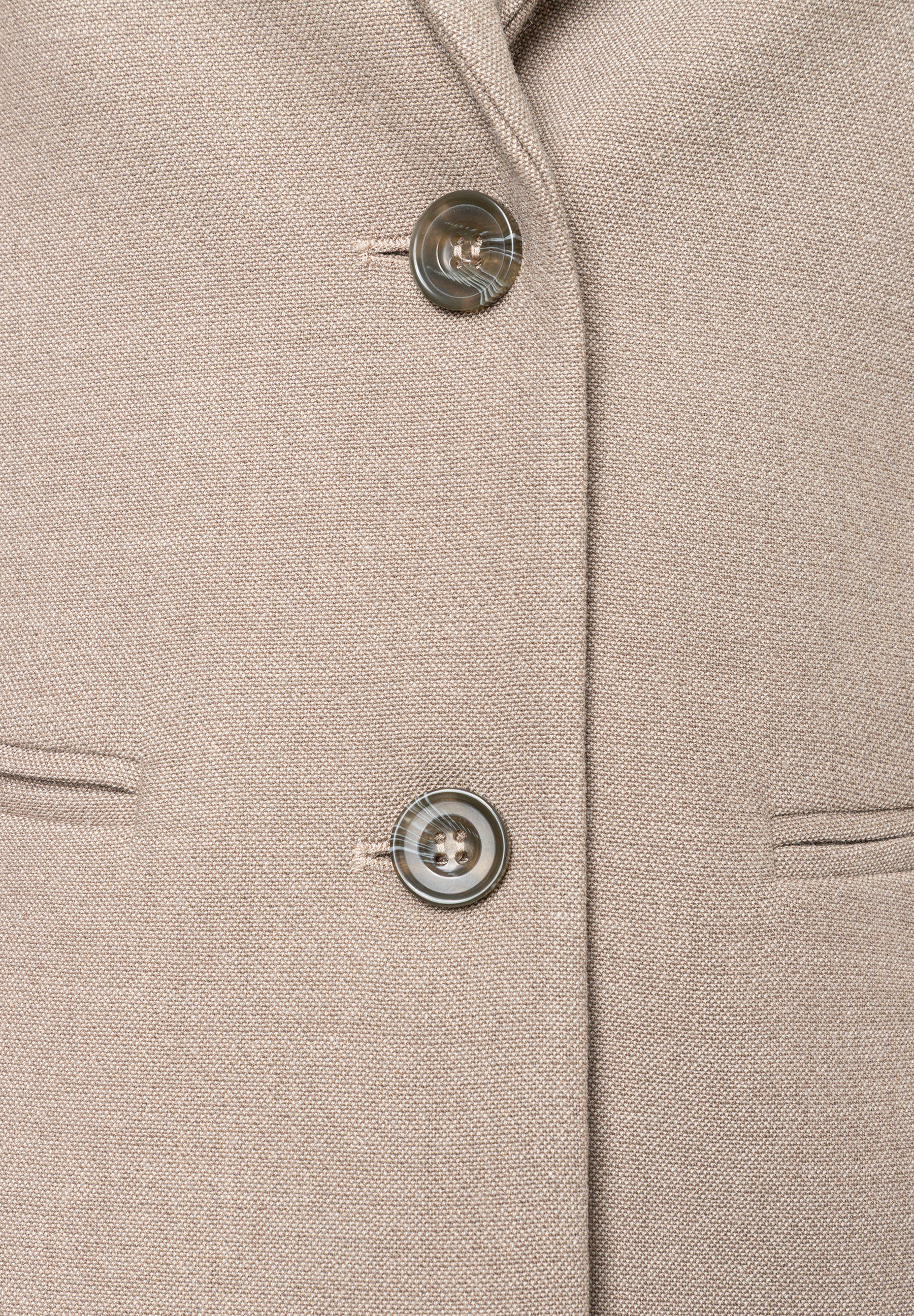 Nahaufnahme des beigefarbenen MORE & MORE Blazers, der durch zwei Knöpfe geschlossen wird, und schräger Seitentaschen.