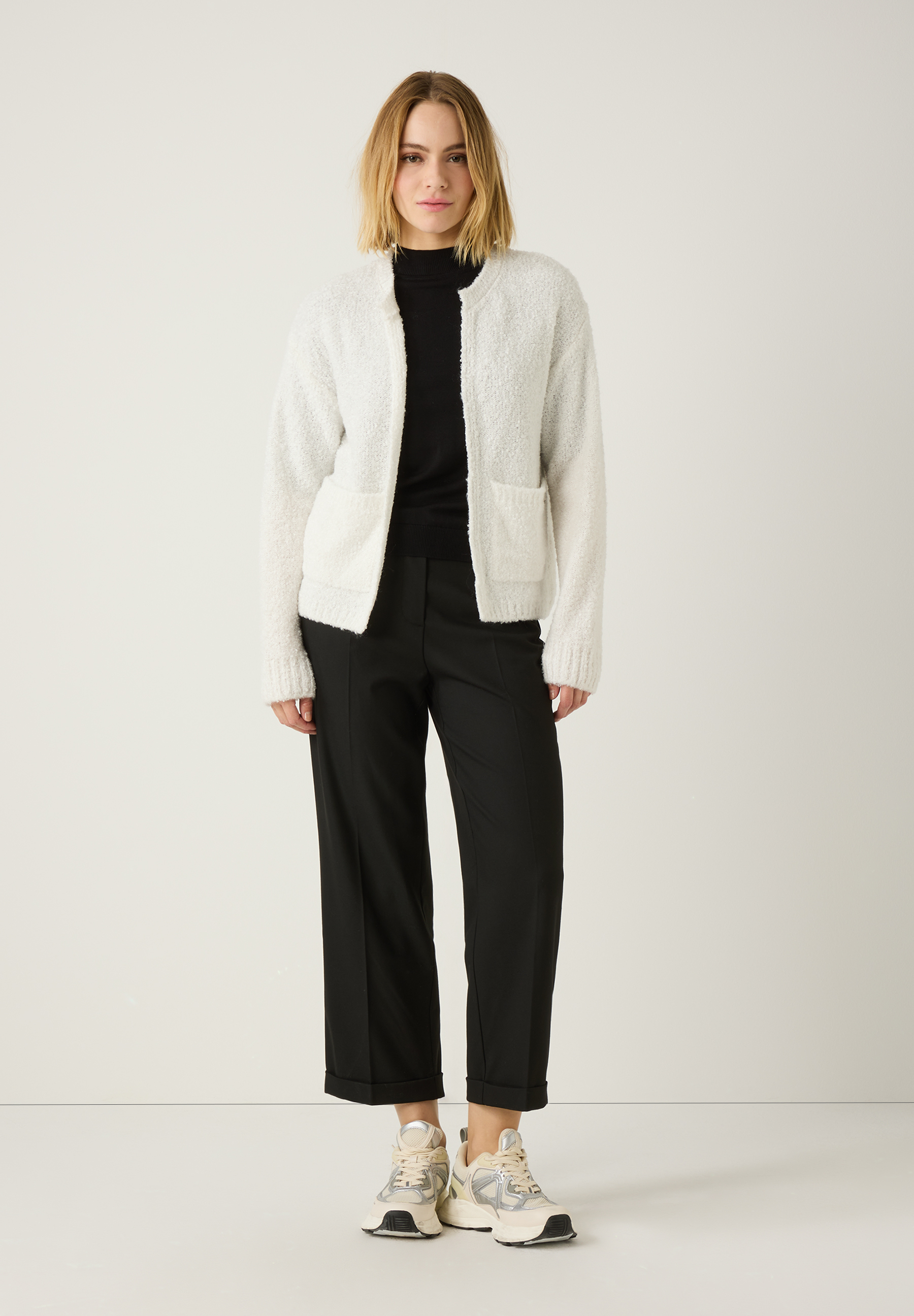 Eine Frau, die MORE & MORE Hosen aus Viskosemischung, einen schwarzen Rolli und eine helle Strickjacke trägt. Eine Frau, die MORE & MORE Hosen aus Viskosemischung, einen schwarzen Rolli und eine helle Strickjacke trägt.