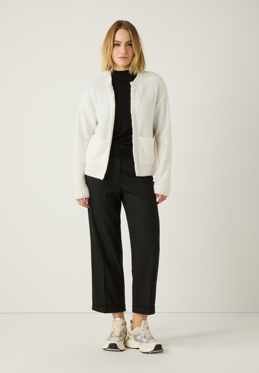 Eine Frau, die MORE & MORE Hosen aus Viskosemischung, einen schwarzen Rolli und eine helle Strickjacke trägt. Eine Frau, die MORE & MORE Hosen aus Viskosemischung, einen schwarzen Rolli und eine helle Strickjacke trägt.