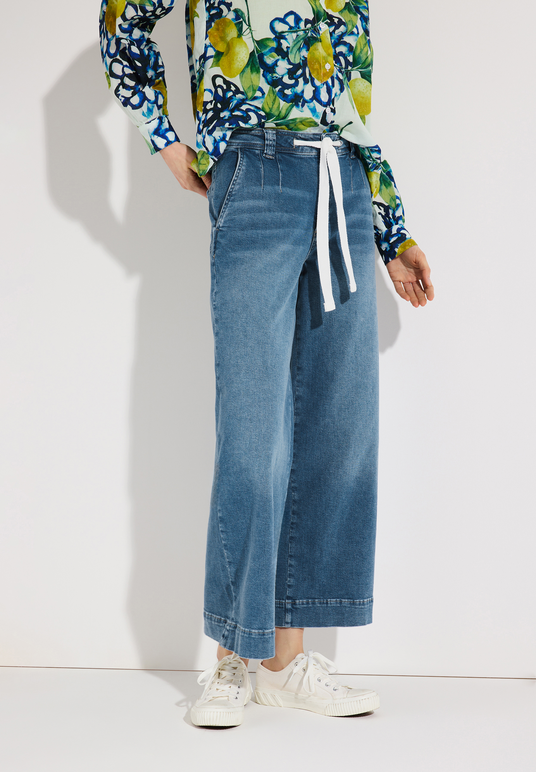 Eine MORE & MORE Jeanshose aus Denim mit weitem Bein und weißem Kordelzug am Bund. Eine MORE & MORE Jeanshose aus Denim mit weitem Bein und weißem Kordelzug am Bund.