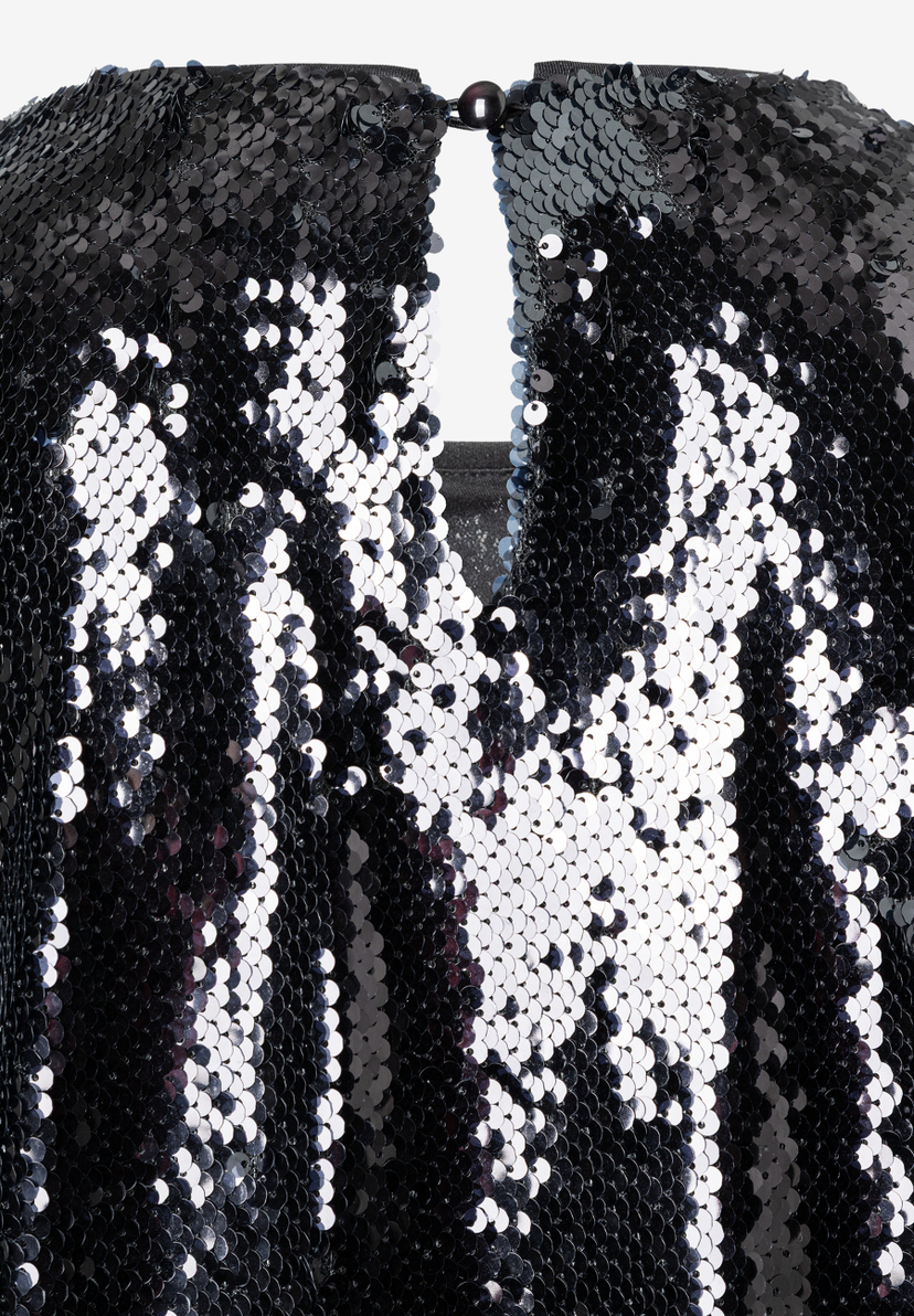 Nahaufnahme eines paillettenbesetzten MORE & MORE Oberteils. Blick auf Ausschnitt mit Knopf im Nacken. Nahaufnahme eines paillettenbesetzten MORE & MORE Oberteils. Blick auf Ausschnitt mit Knopf im Nacken.