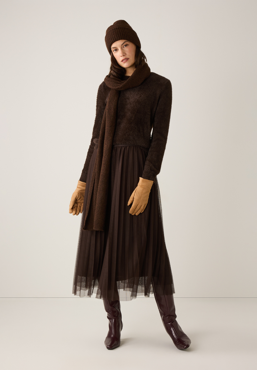 Ein Model in Strick von MORE & MORE: Mütze, Schal, Pullover, Handschuhe, Rock und Stiefel in verschiedenen Brauntönen. Ein Model in Strick von MORE & MORE: Mütze, Schal, Pullover, Handschuhe, Rock und Stiefel in verschiedenen Brauntönen.