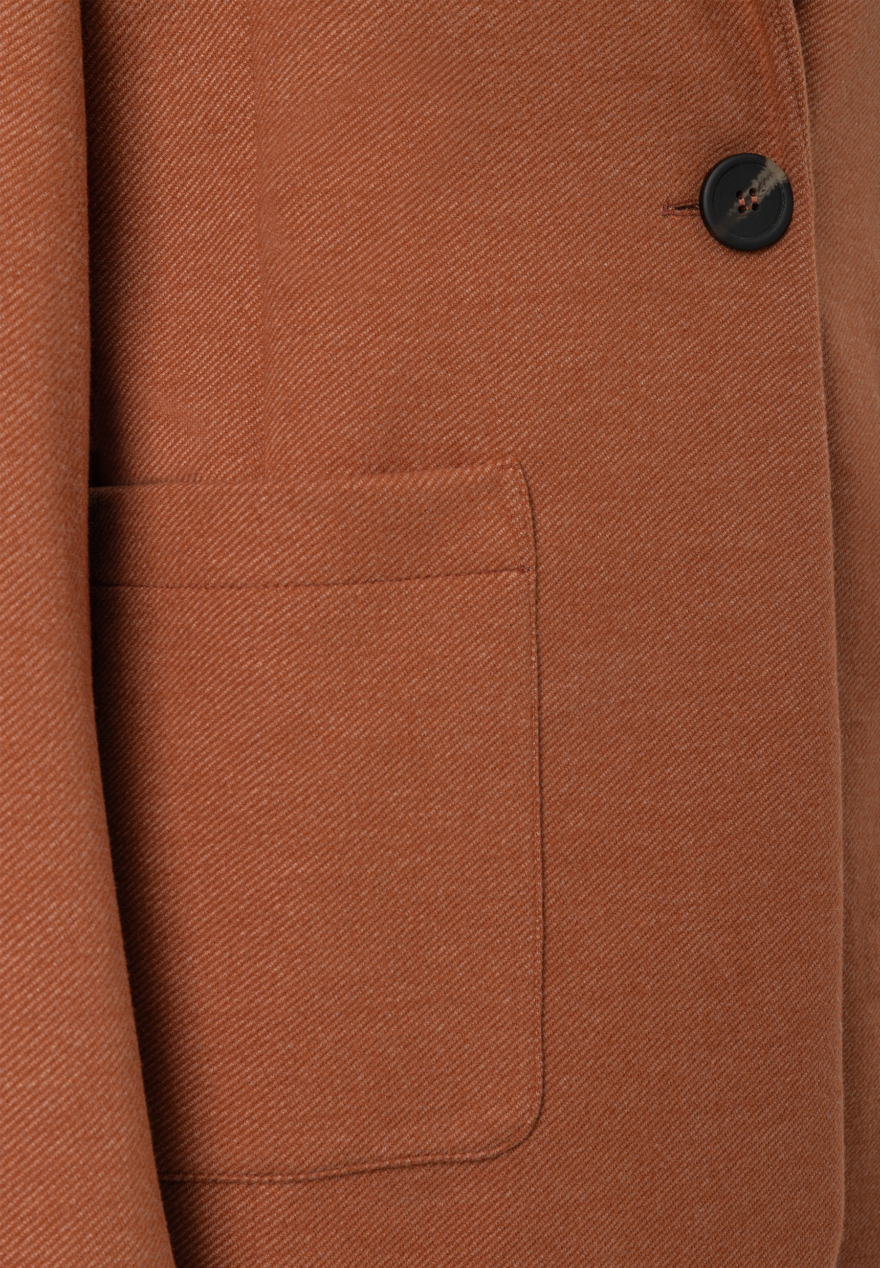 MORE & MORE Blazer in Rostbraun, Detailansicht: Stoff mit diagonalem Muster, eine Tasche und ein dunkler Knopf. MORE & MORE Blazer in Rostbraun, Detailansicht: Stoff mit diagonalem Muster, eine Tasche und ein dunkler Knopf.