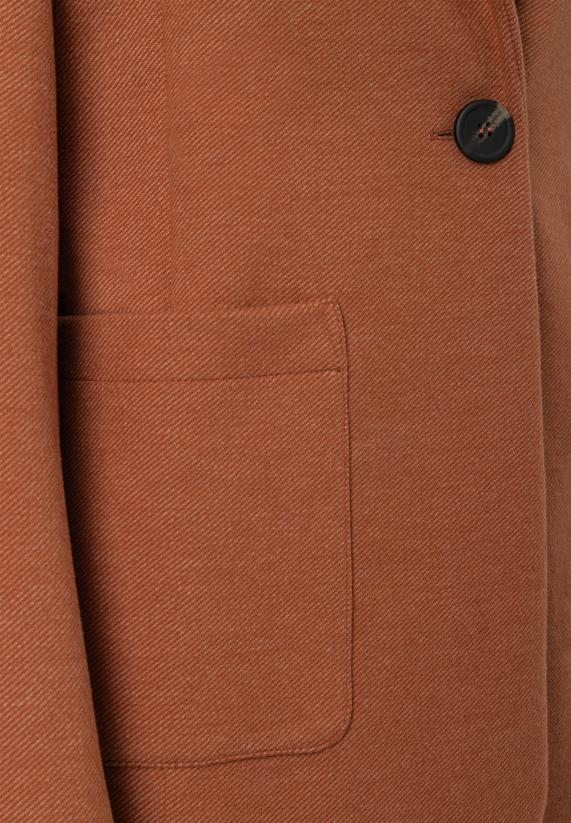 MORE & MORE Blazer in Rostbraun, Detailansicht: Stoff mit diagonalem Muster, eine Tasche und ein dunkler Knopf. MORE & MORE Blazer in Rostbraun, Detailansicht: Stoff mit diagonalem Muster, eine Tasche und ein dunkler Knopf.