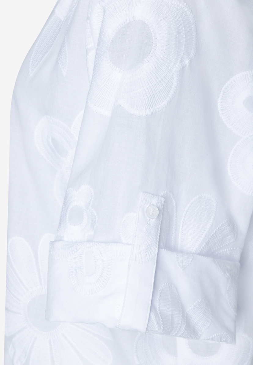 Nahaufnahme einer weißen MORE & MORE Bluse mit floralen Stickereien und Knopf am Ärmel. Nahaufnahme einer weißen MORE & MORE Bluse mit floralen Stickereien und Knopf am Ärmel.