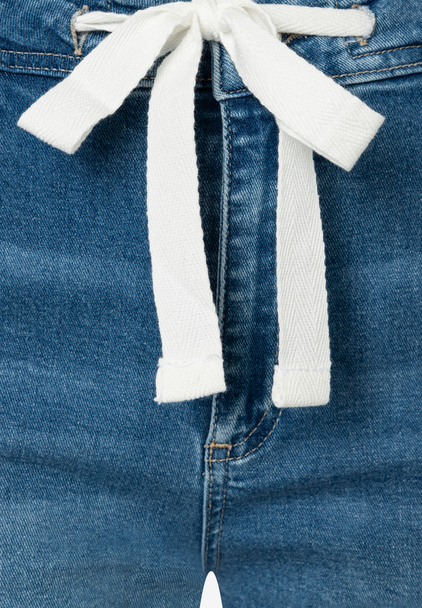 Nahaufnahme einer MORE & MORE Jeanshose mit weißem Kordelzug und elastischem Denim-Material. Nahaufnahme einer MORE & MORE Jeanshose mit weißem Kordelzug und elastischem Denim-Material.