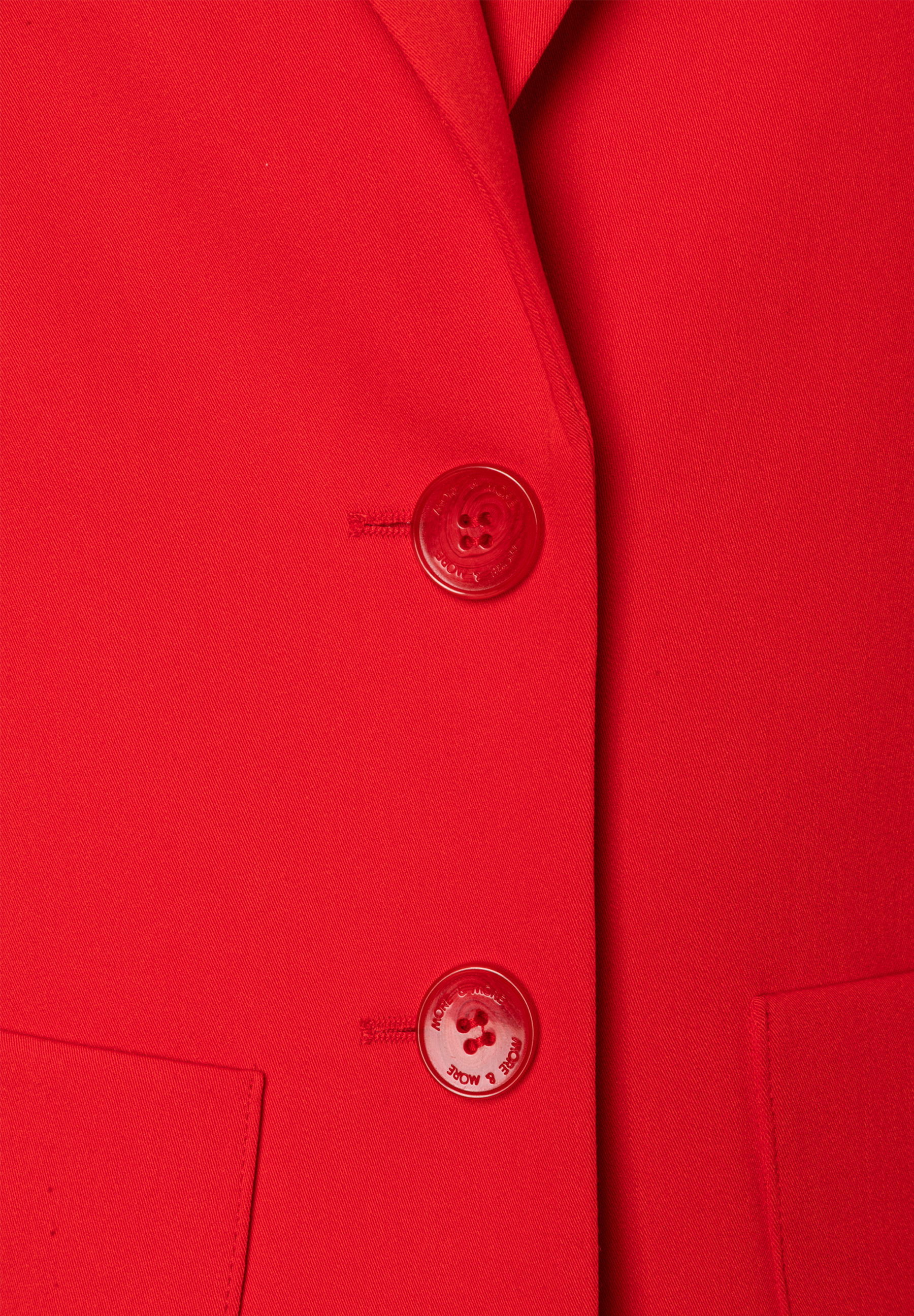 Nahaufnahme eines roten MORE & MORE Blazers mit zwei Knöpfen und einer kleinen Tasche. Nahaufnahme eines roten MORE & MORE Blazers mit zwei Knöpfen und einer kleinen Tasche.