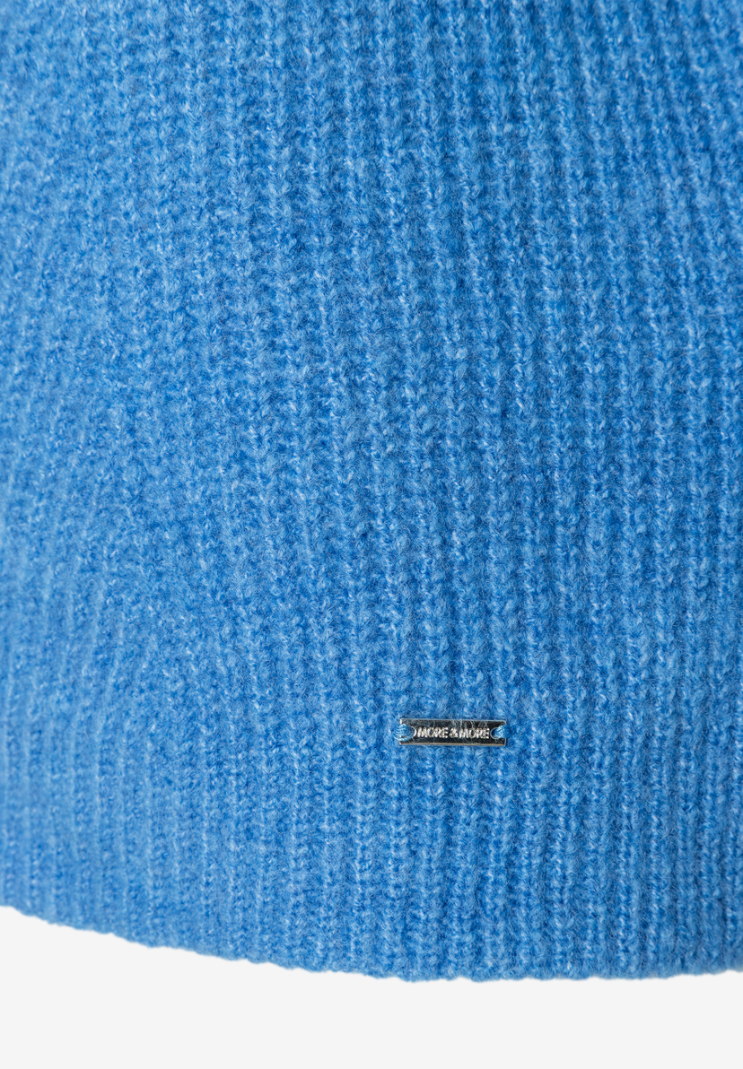 Nahaufnahme eines blauen Rippstrick-Oberteils von MORE & MORE mit kleinem Markenlogo. Nahaufnahme eines blauen Rippstrick-Oberteils von MORE & MORE mit kleinem Markenlogo.