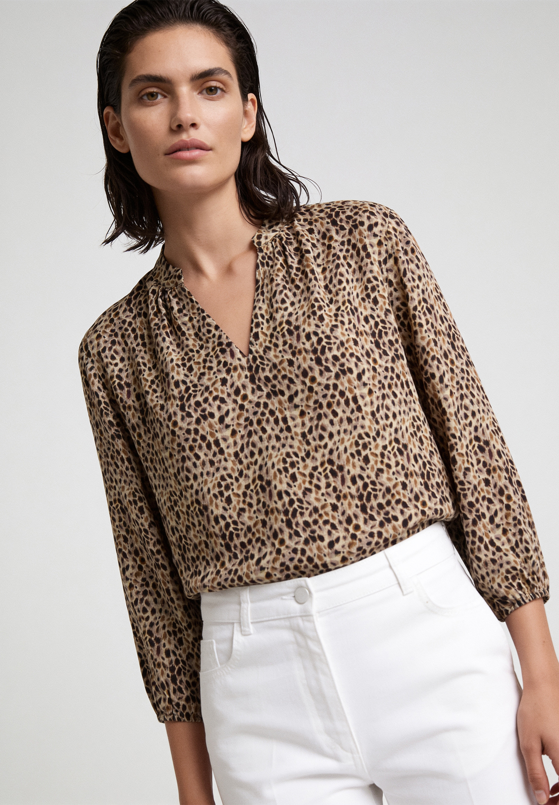 AI generated - MORE & MORE Bluse mit Leopardenmuster, V-Ausschnitt, 3/4-Ärmeln, kombiniert mit weißer Hose auf weißem Hintergrund.
