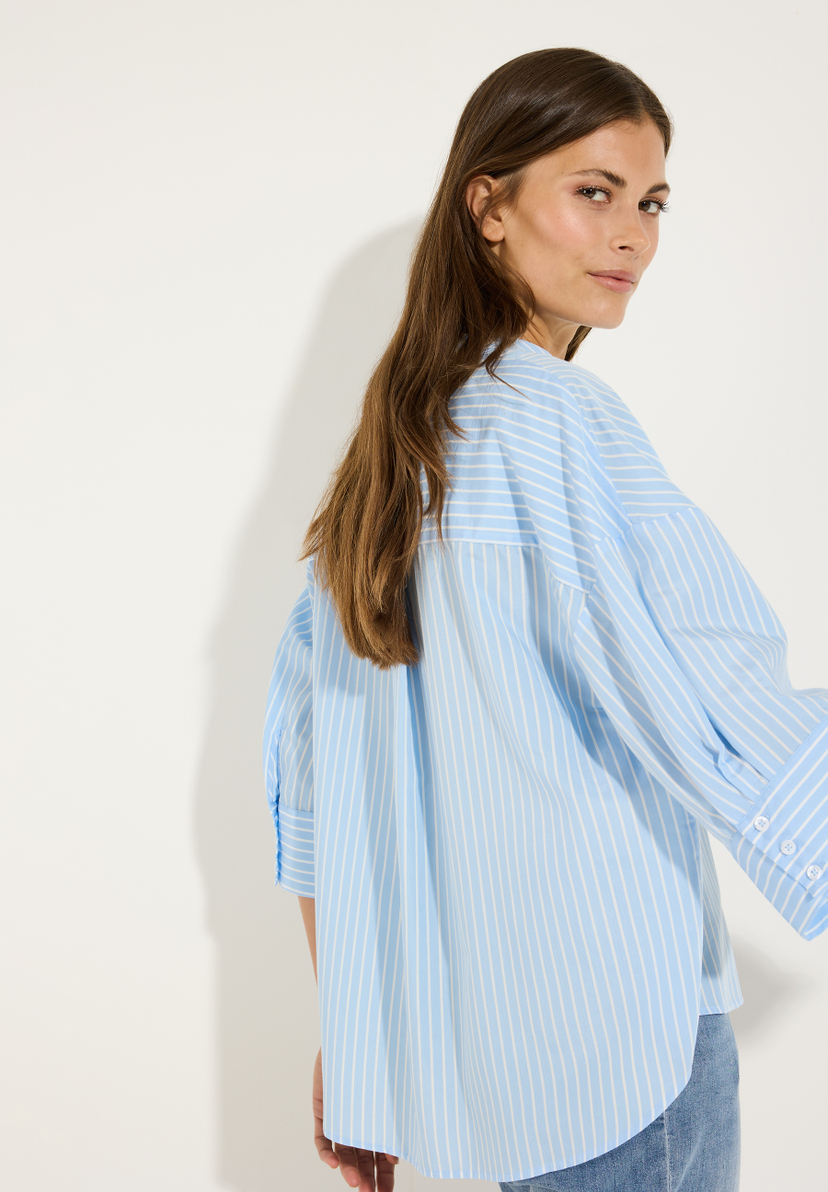 MORE & MORE Bluse: Eine Frau trägt eine blau-weiß gestreifte Popeline-Bluse aus elastischem Material. MORE & MORE Bluse: Eine Frau trägt eine blau-weiß gestreifte Popeline-Bluse aus elastischem Material.