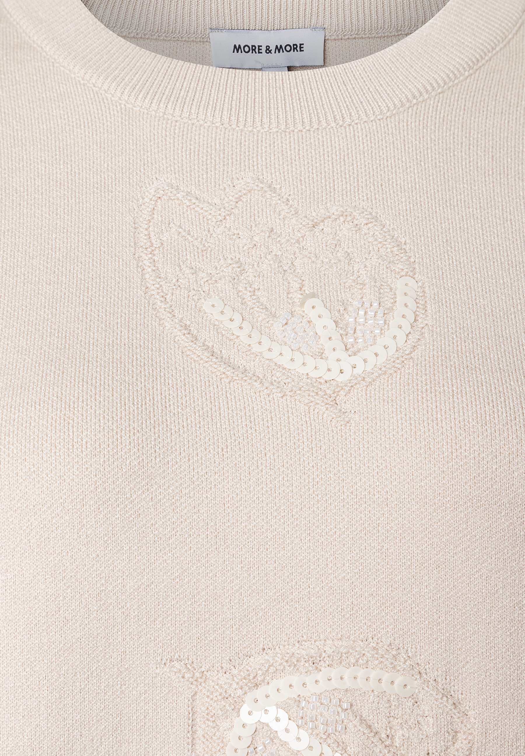 Nahaufnahme eines MORE & MORE Strickpullovers mit Herzapplikationen aus Pailletten. Nahaufnahme eines MORE & MORE Strickpullovers mit Herzapplikationen aus Pailletten.