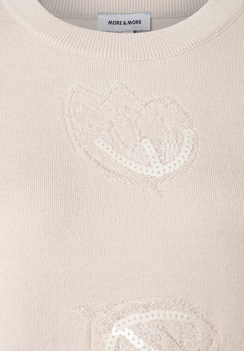 Nahaufnahme eines MORE & MORE Strickpullovers mit Herzapplikationen aus Pailletten. Nahaufnahme eines MORE & MORE Strickpullovers mit Herzapplikationen aus Pailletten.