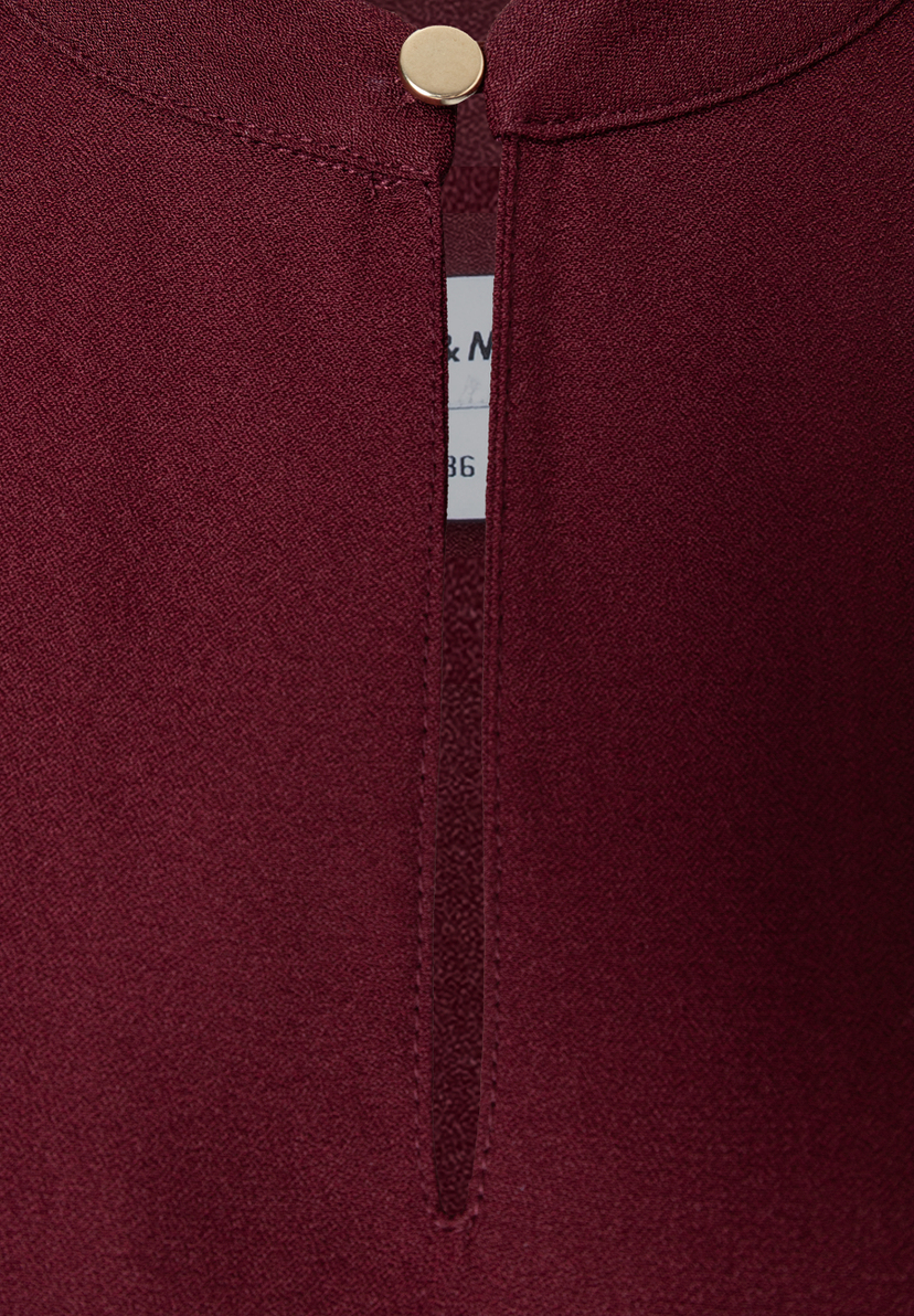 MORE & MORE Bluse: Eine Nahaufnahme der eleganten, bordeauxroten Bluse mit goldenem Knopfdetail und einem kleinen Schlitz. MORE & MORE Bluse: Eine Nahaufnahme der eleganten, bordeauxroten Bluse mit goldenem Knopfdetail und einem kleinen Schlitz.