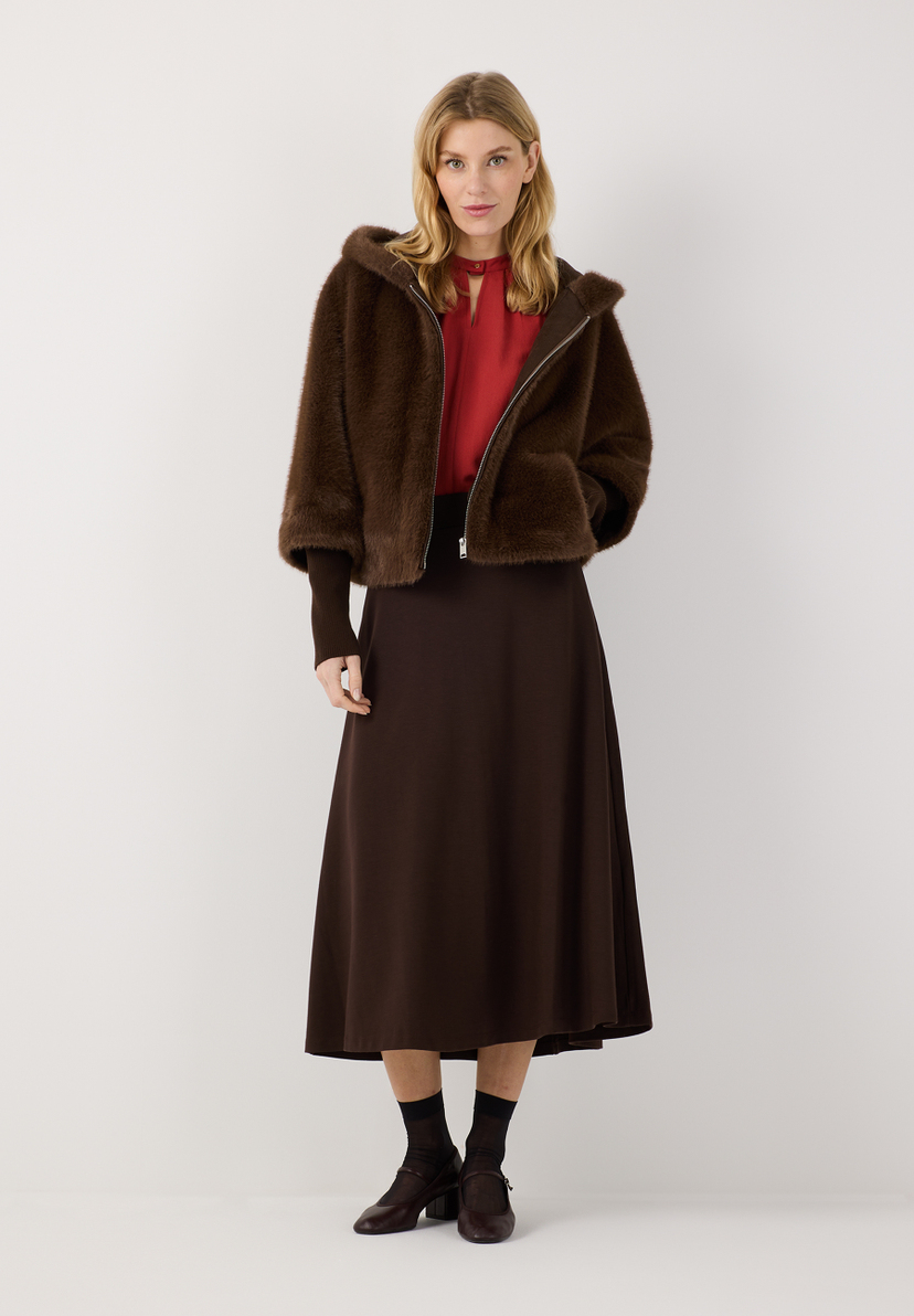 MORE & MORE Kurzjacke aus Kunstpelz, Braun, mit Kapuze und Reißverschluss, kombiniert mit roter Bluse & braunem Rock.