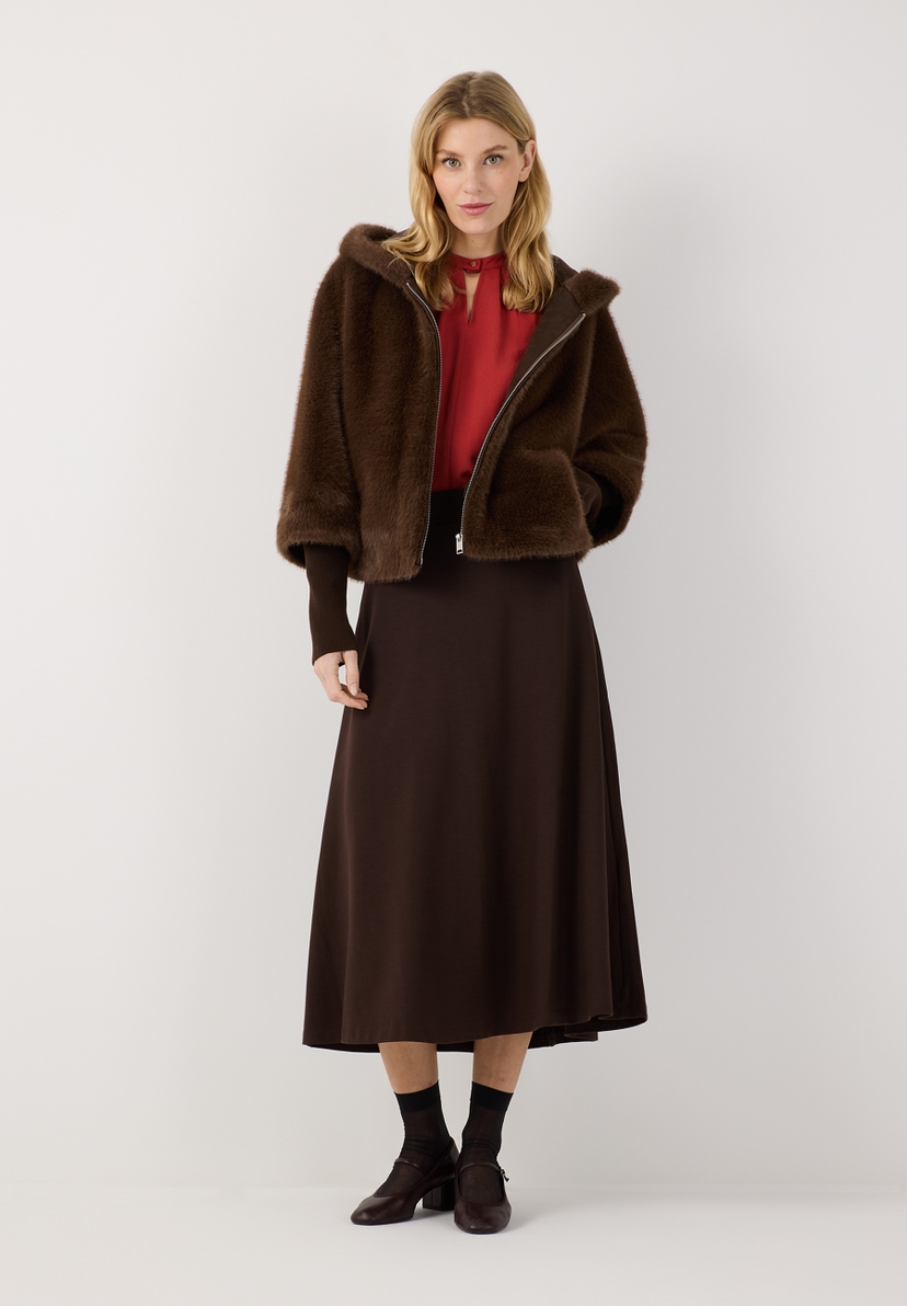 MORE & MORE Kurzjacke aus Kunstpelz, Braun, mit Kapuze und Reißverschluss, kombiniert mit roter Bluse & braunem Rock. MORE & MORE Kurzjacke aus Kunstpelz, Braun, mit Kapuze und Reißverschluss, kombiniert mit roter Bluse & braunem Rock.