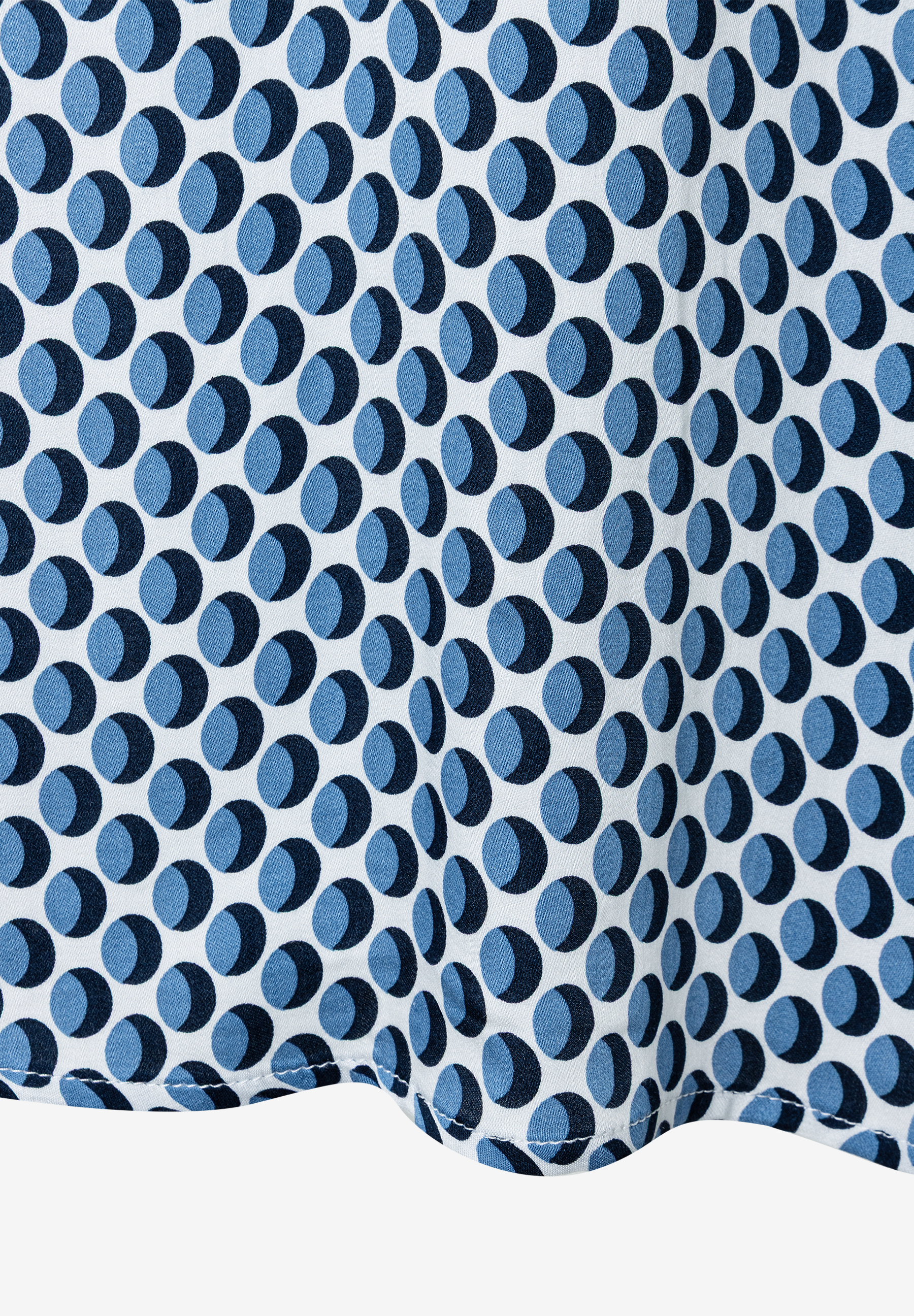 Nahaufnahme einer MORE & MORE Bluse mit blauem Punktmuster auf weißem Grund. Nahaufnahme einer MORE & MORE Bluse mit blauem Punktmuster auf weißem Grund.