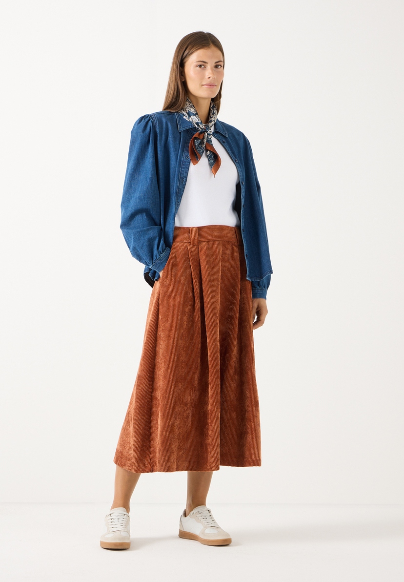 MORE & MORE Accessoires: Eine Frau trägt ein gemustertes Halstuch, eine Jeansjacke und einen rostbraunen Cordrock.