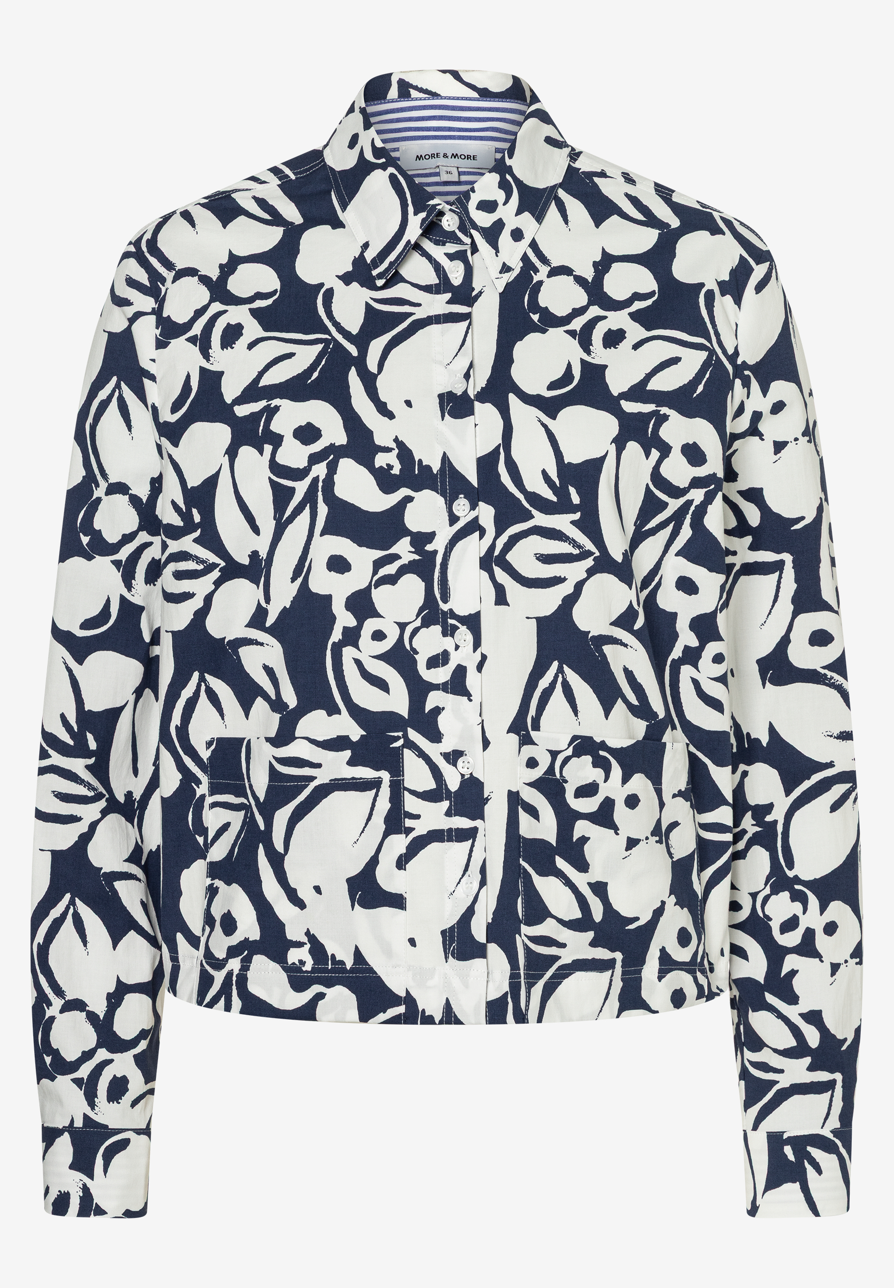 Eine MORE & MORE Bluse mit einem weißen Blumenmuster auf blauem Grund, langen Ärmeln und zwei Brusttaschen. Eine MORE & MORE Bluse mit einem weißen Blumenmuster auf blauem Grund, langen Ärmeln und zwei Brusttaschen.