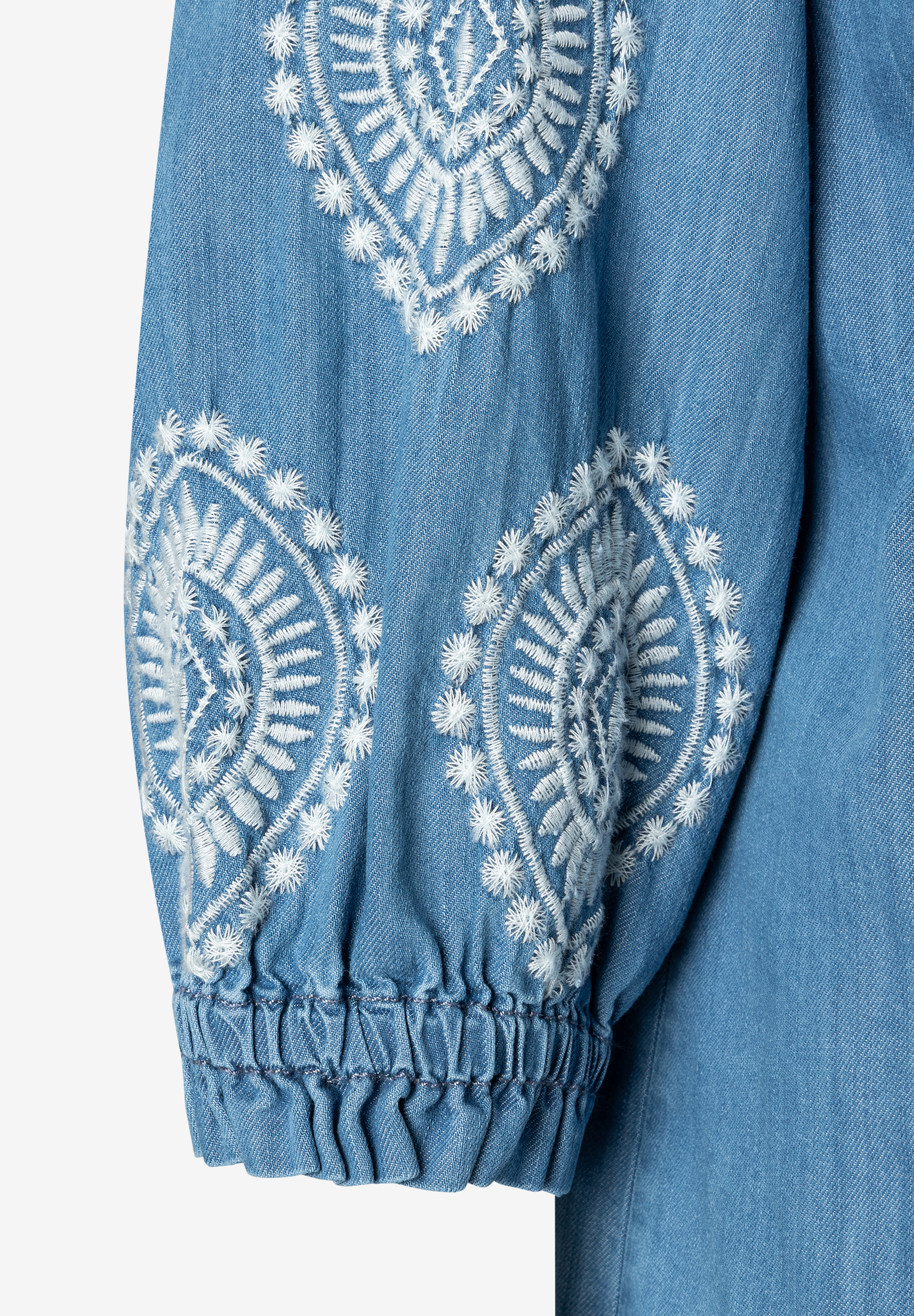 Ein Ärmel der MORE & MORE Bluse aus Denim mit weißer Stickerei. Ein Ärmel der MORE & MORE Bluse aus Denim mit weißer Stickerei.