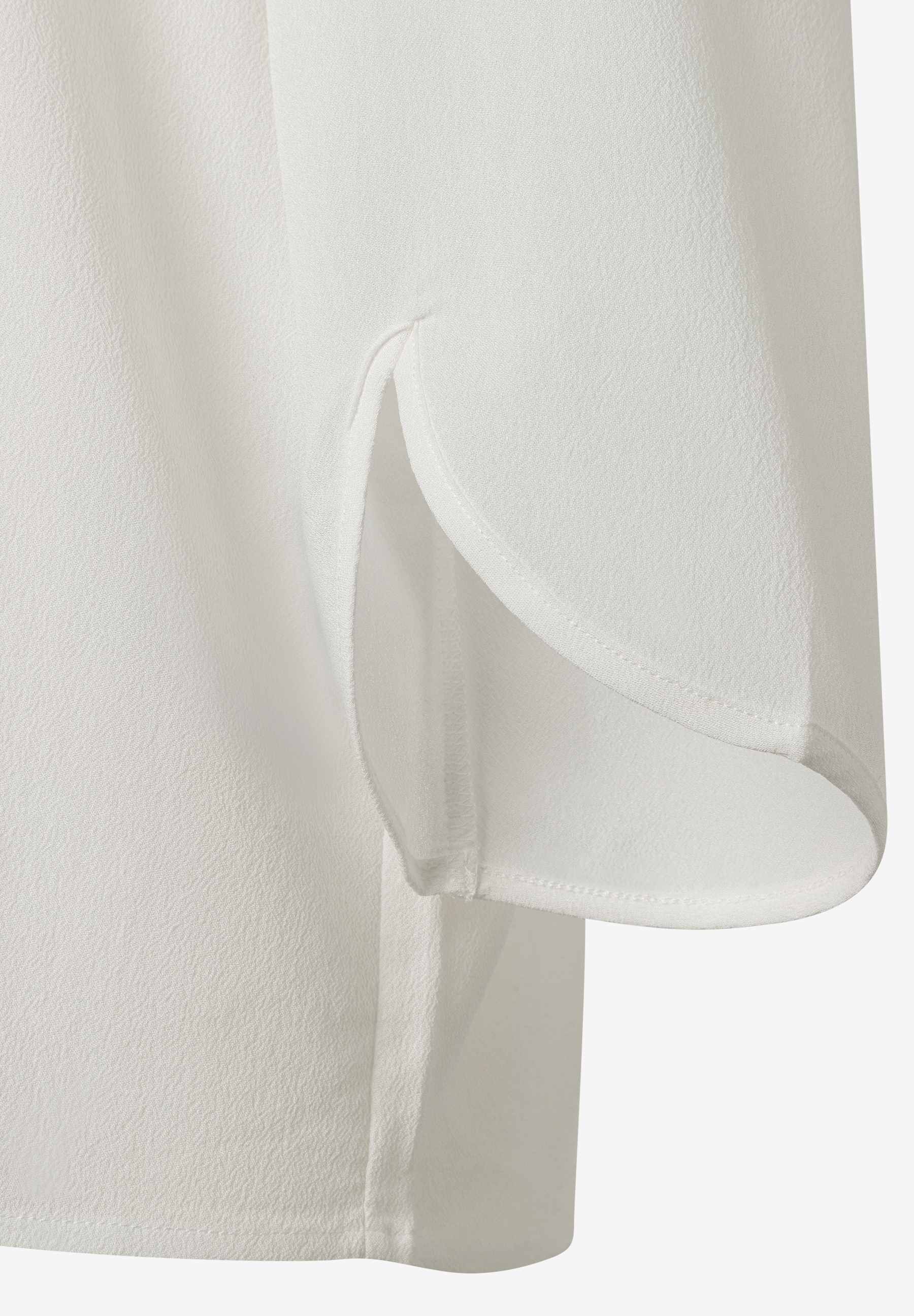 Nahaufnahme einer weißen MORE & MORE Bluse aus Viskose-Crêpe-Webware mit Seitenschlitz. Nahaufnahme einer weißen MORE & MORE Bluse aus Viskose-Crêpe-Webware mit Seitenschlitz.