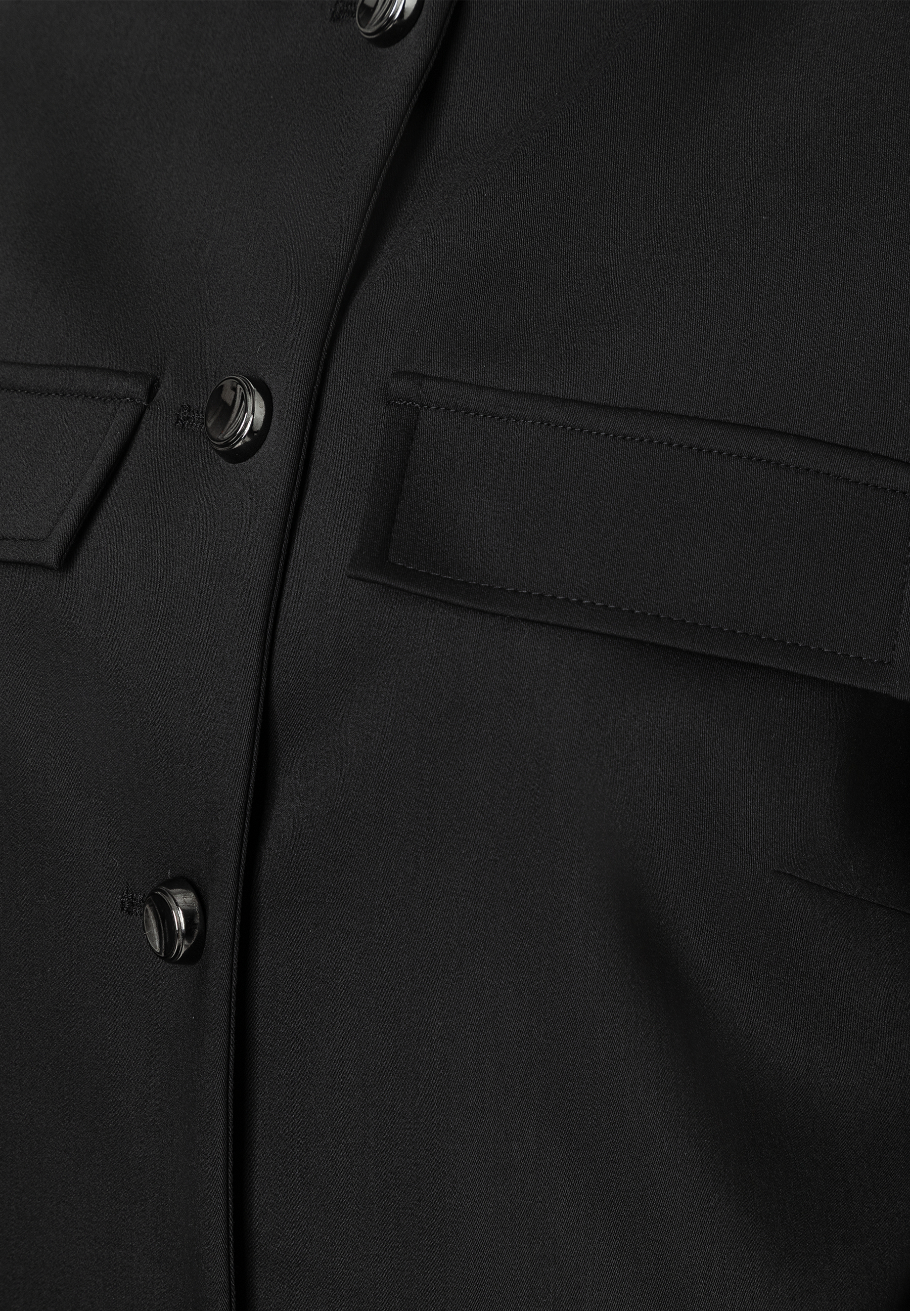 Nahaufnahme eines schwarzen MORE & MORE Blazers mit Knöpfen und einer Tasche. Nahaufnahme eines schwarzen MORE & MORE Blazers mit Knöpfen und einer Tasche.