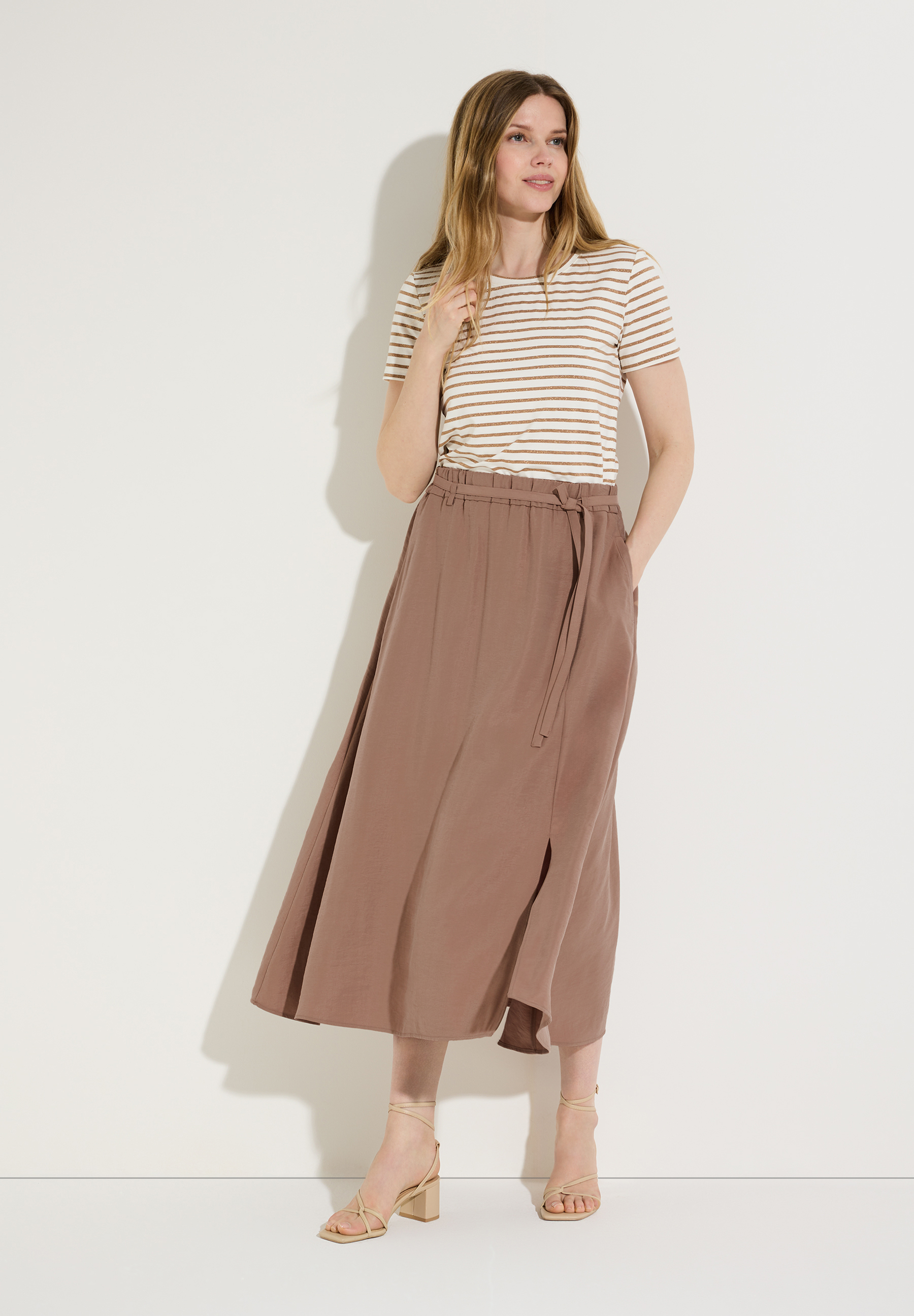 Eine Frau mit einem MORE & MORE Rock aus fließender Webware. Der Rock ist knöchellang mit Schlitz und Bindegürtel.