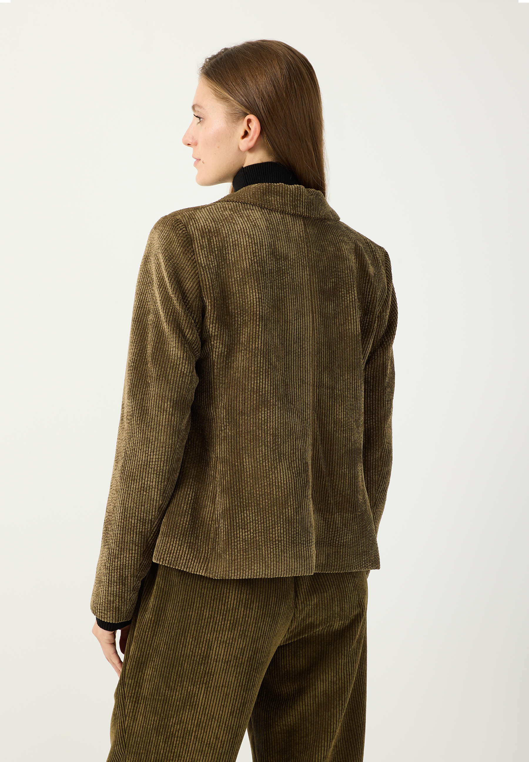 MORE & MORE Blazer in Dunkelgrün aus Cord. Eine schlanke Frau mit braunen Haaren und einem schwarzen Rollkragenpullover trägt den Blazer. MORE & MORE Blazer in Dunkelgrün aus Cord. Eine schlanke Frau mit braunen Haaren und einem schwarzen Rollkragenpullover trägt den Blazer.